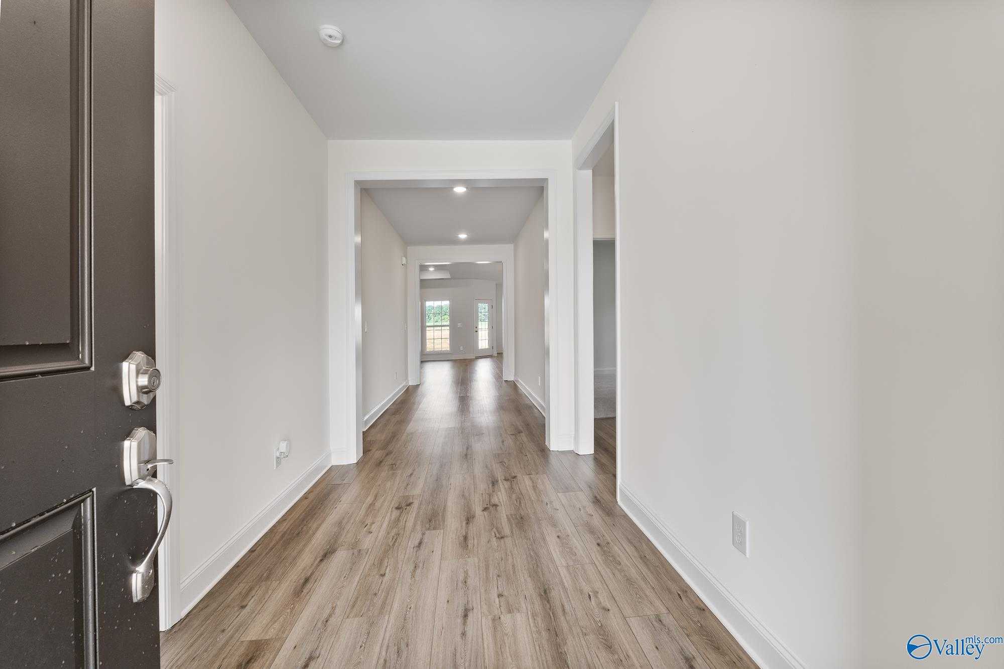 Bright entry hallway with light wood floors and open archways in Davidson Homes The Harrison, Pikes Ridge, Alabama