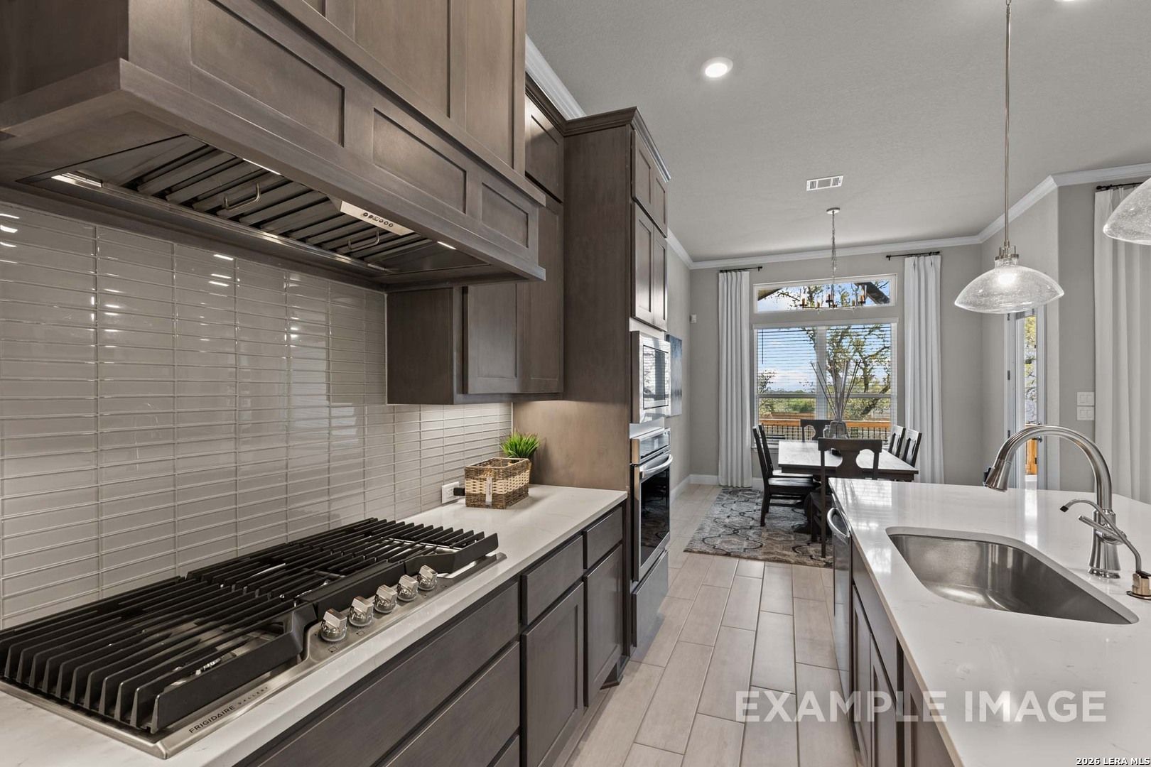 Gourmet kitchen with gas cooktop and island in The Garner C floor plan at The Reserve at Potranco Oaks, Castroville, TX.