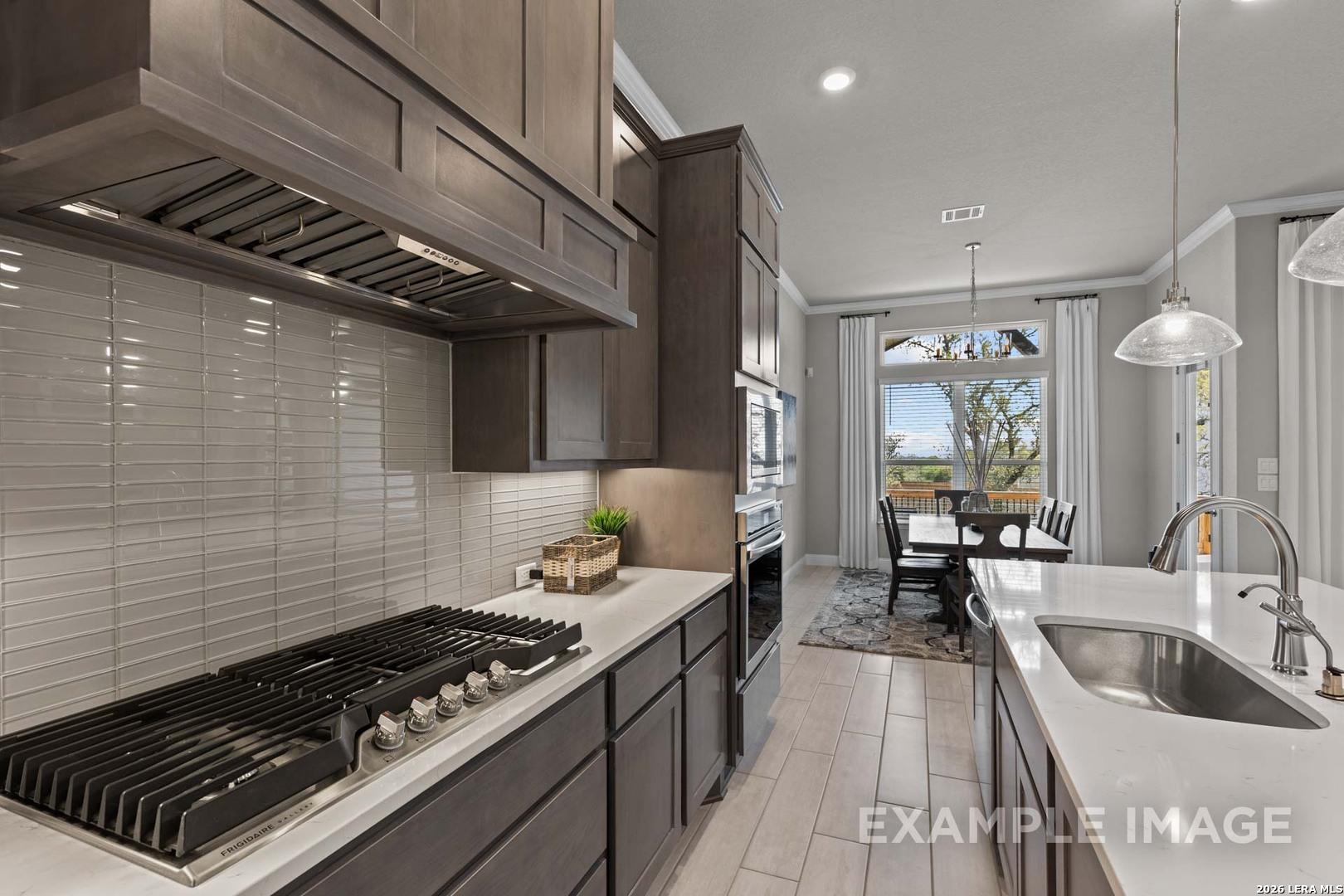 Gourmet kitchen with gas cooktop and island in The Garner C floor plan at The Reserve at Potranco Oaks, Castroville, TX.