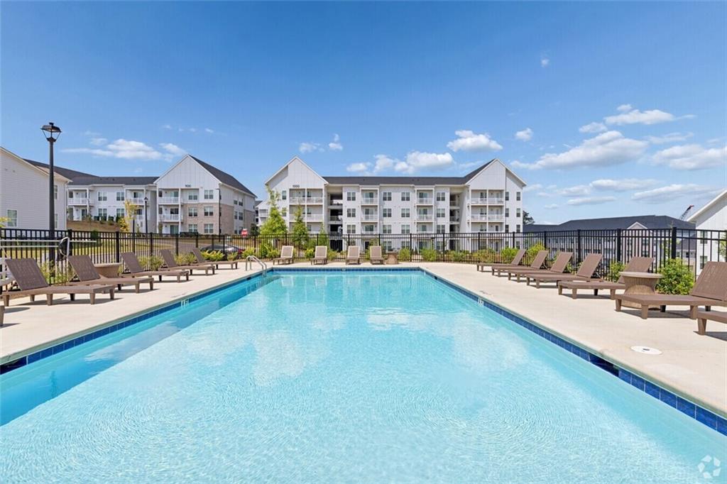 Community swimming pool with lounge chairs surrounded by apartment buildings at Stegall Village, Davidson Homes community in Emerson, Georgia