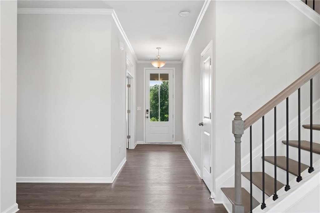 Bright entry hallway with hardwood floors, glass-front door, and oak staircase in Davidson Homes The Hickory B, Winder, GA
