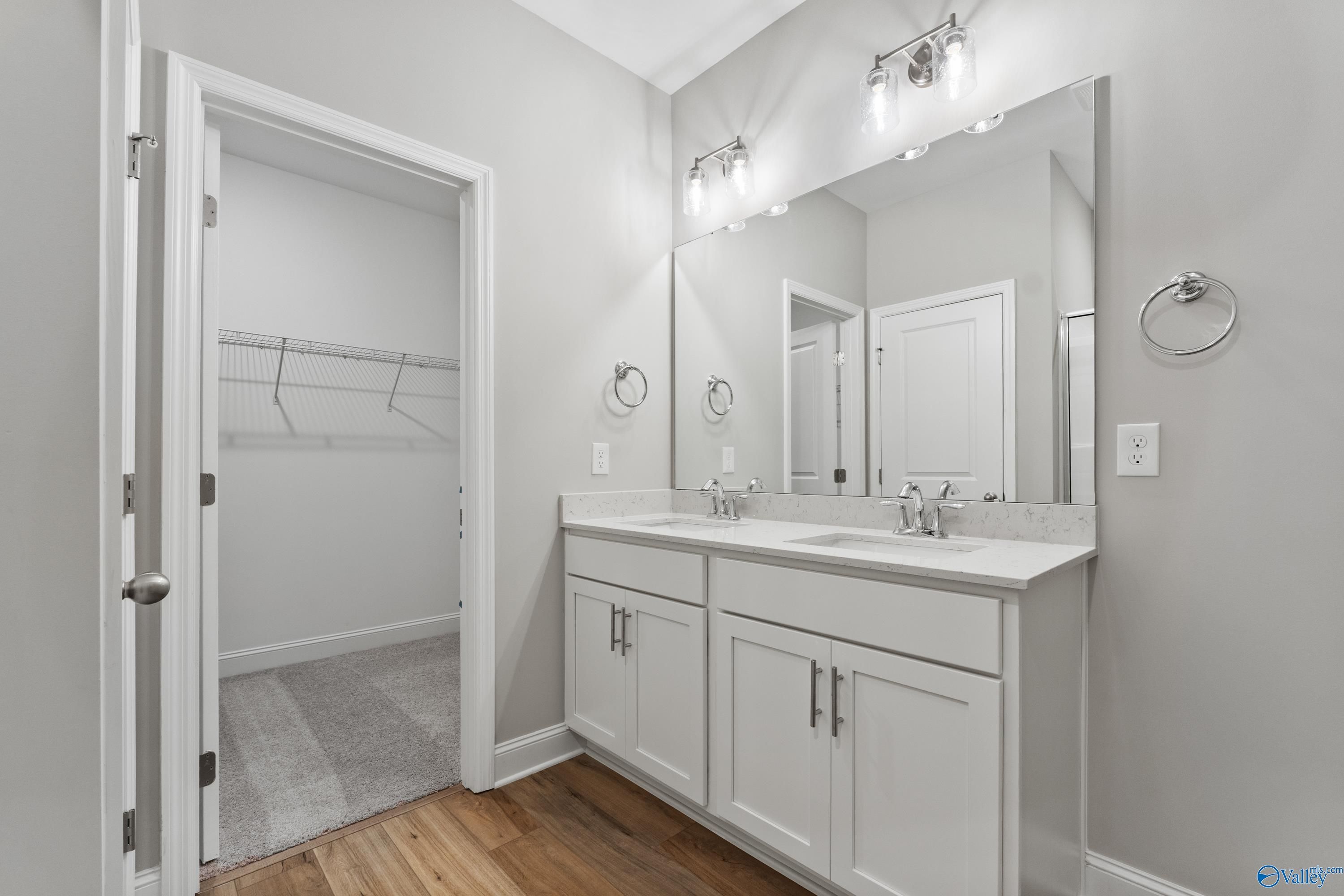 Elegant master bathroom featuring double vanity, large mirrors, sconce lighting, and walk-in closet in Davidson Homes The Franklin C, Huntsville
