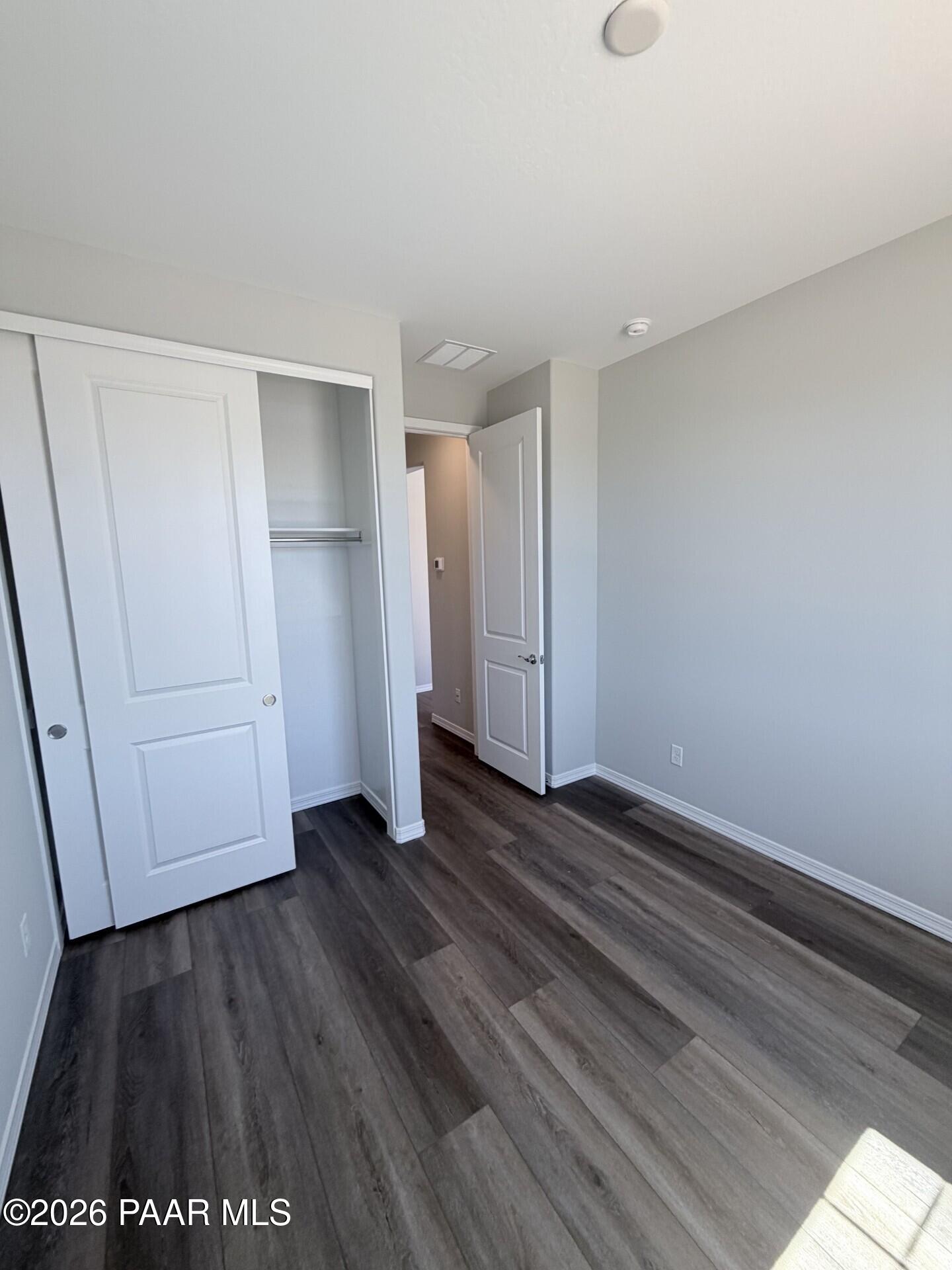 Bright secondary bedroom with wood-look flooring and closet in The Frontier A floor plan by Davidson Homes.