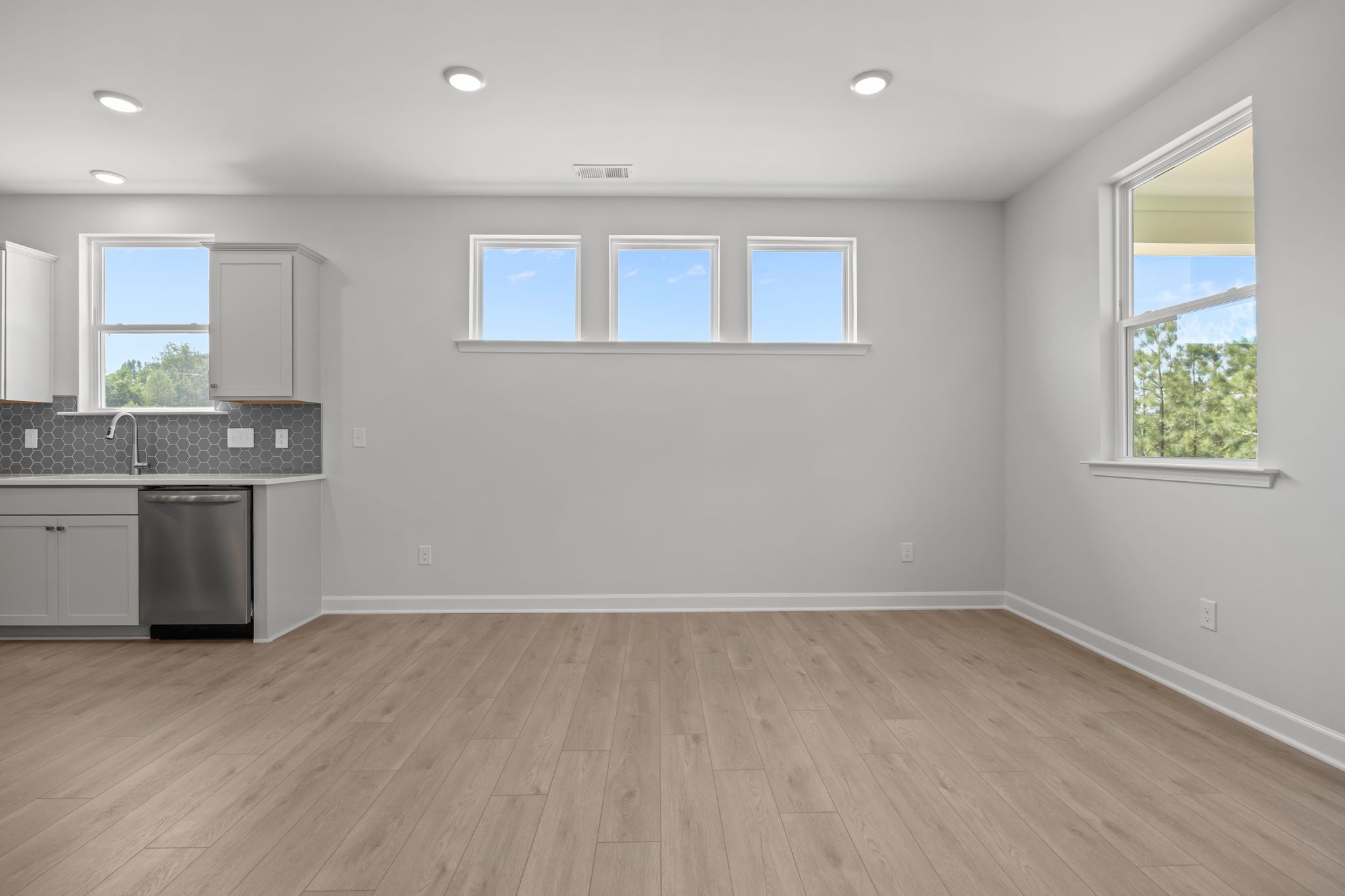 Bright breakfast nook in The Ashport B floor plan featuring wood-style flooring, gray cabinets, and a geometric backsplash.