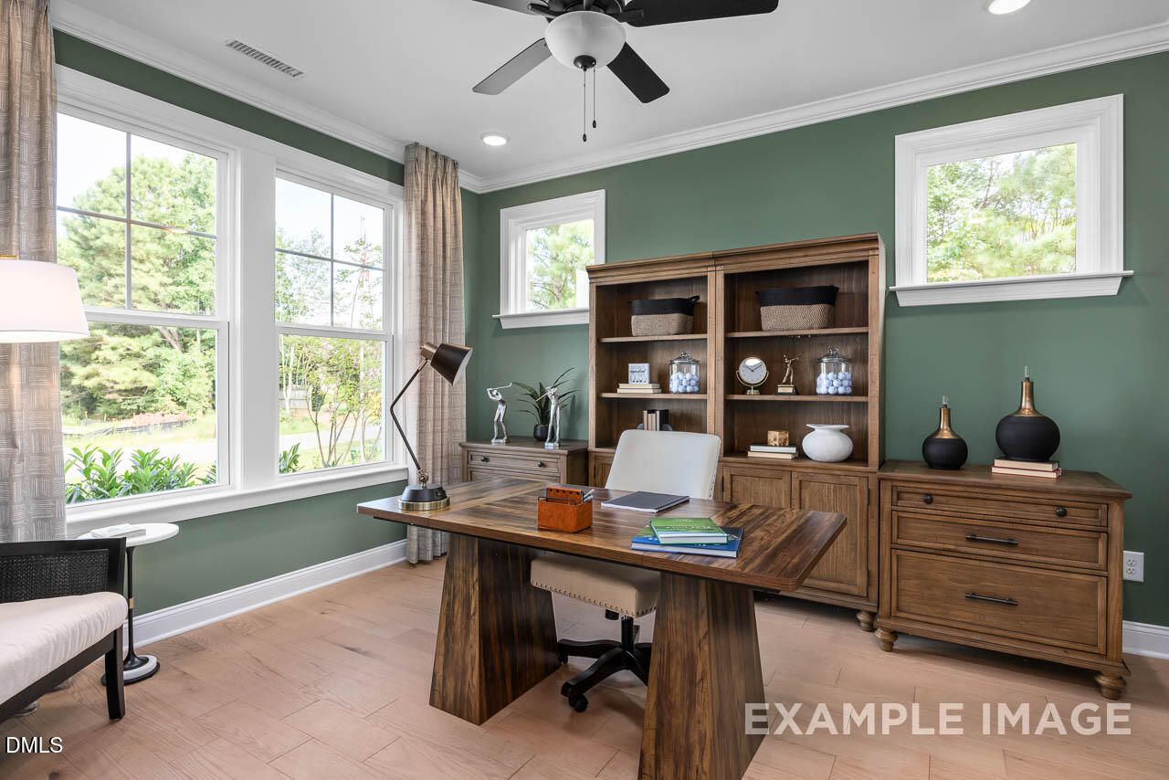 Cozy home office with wooden desk, bookshelves, green walls, and large windows in Davidson Homes The Crawford D, Angier, NC