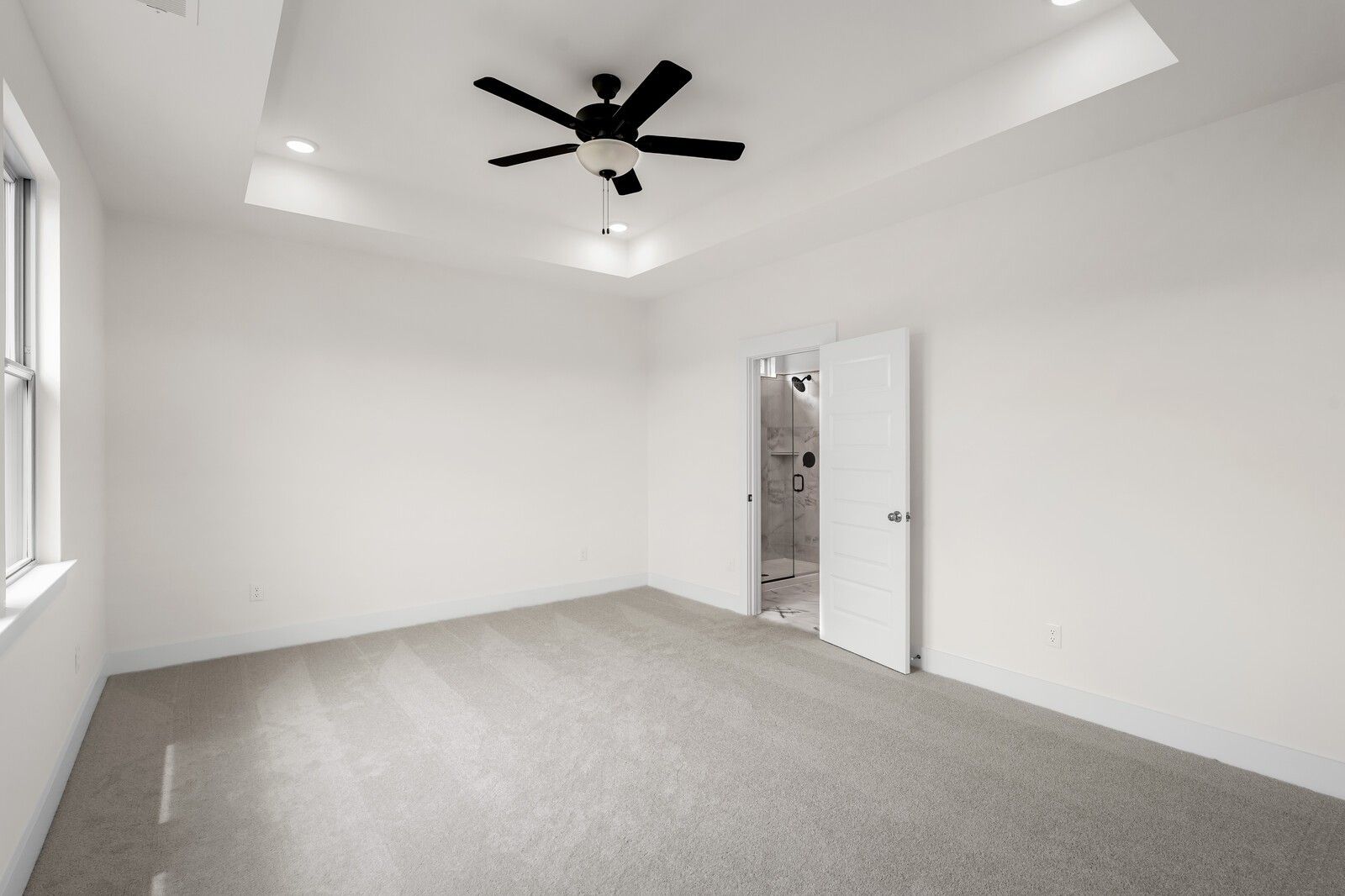 Bright primary bedroom with tray ceiling and ceiling fan in The Prairie C floor plan at Woods Crossing, Gallatin, TN.