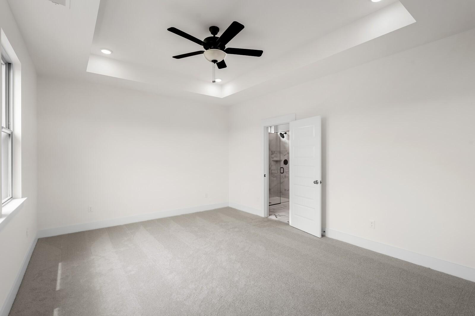 Bright primary bedroom with tray ceiling and ceiling fan in The Prairie C floor plan at Woods Crossing, Gallatin, TN.