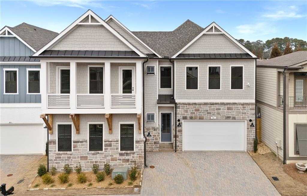 Two-story Davidson Homes Seaside B exterior with 3-car garage, covered porch, stone accents in The Village at Towne Lake, Woodstock, GA