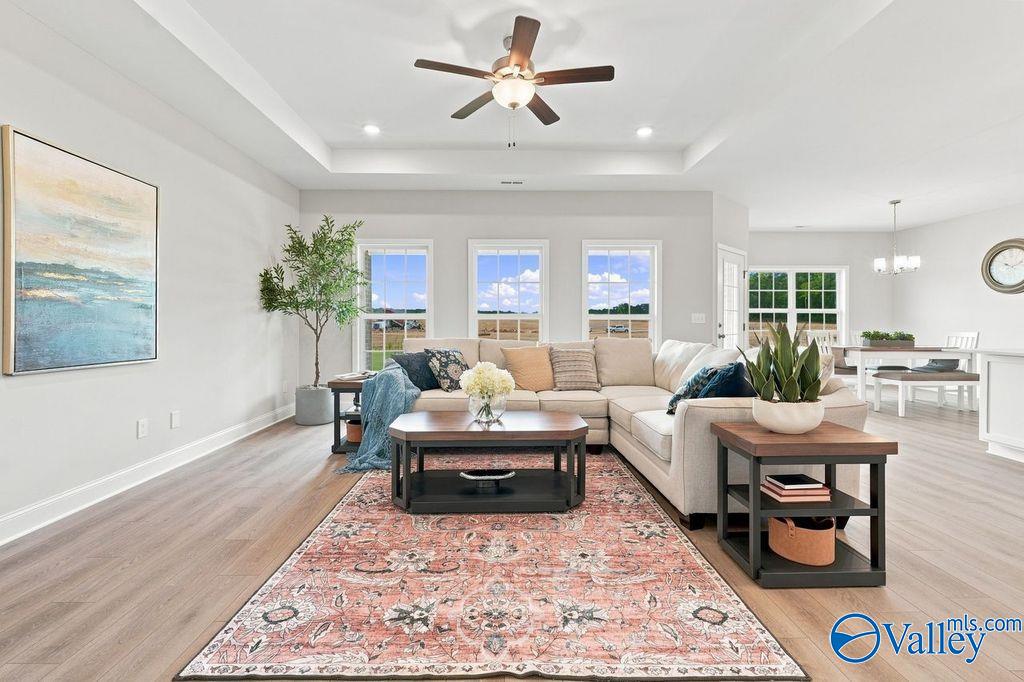 Bright great room with sectional sofa, tray ceiling, and hardwood-style floors in Davidson Homes' The Harrison, Hartselle, Alabama