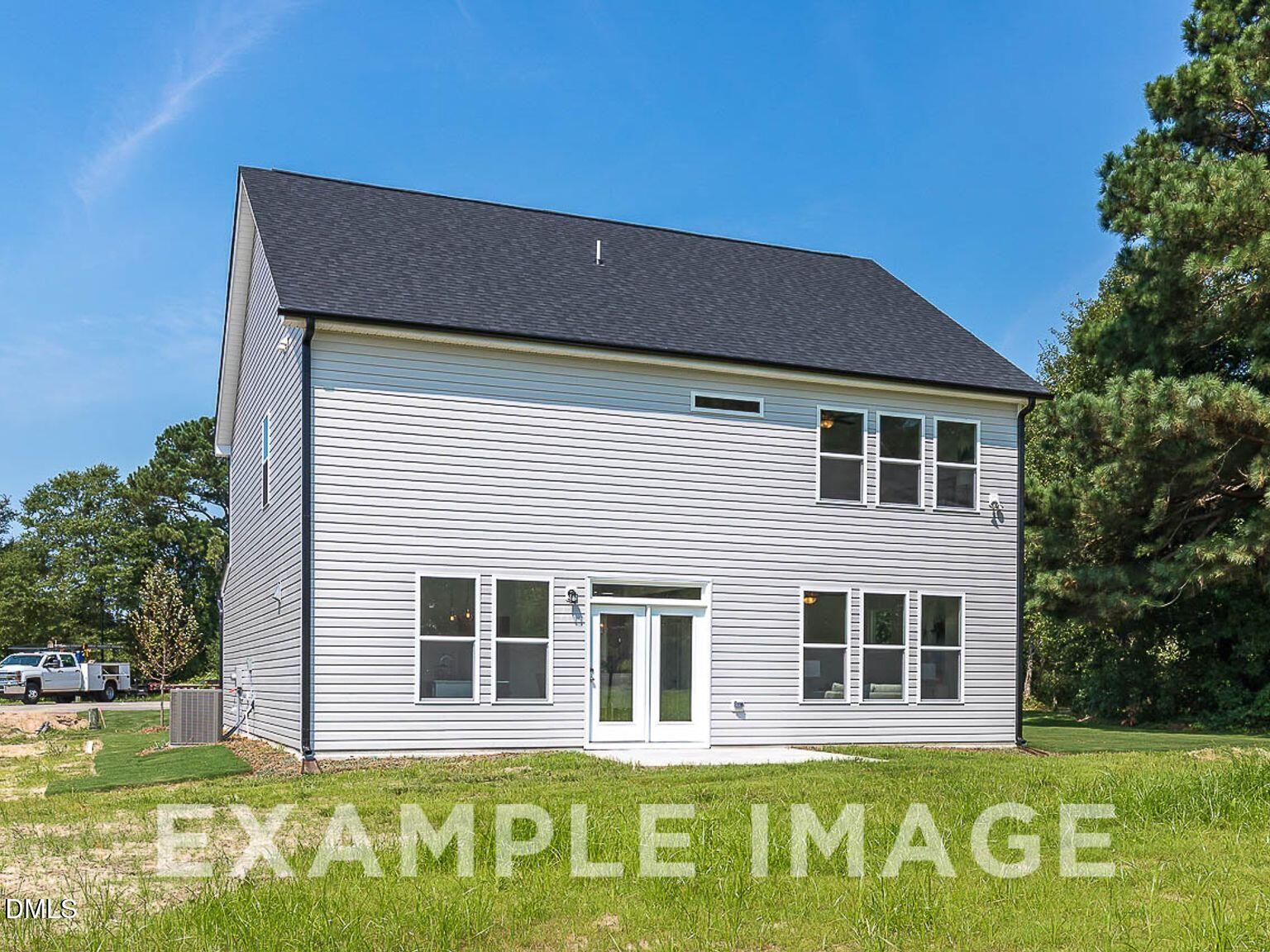 Two-story Chestnut B home exterior with gray siding, black roof, French doors to patio, and pine trees in Lillington, NC