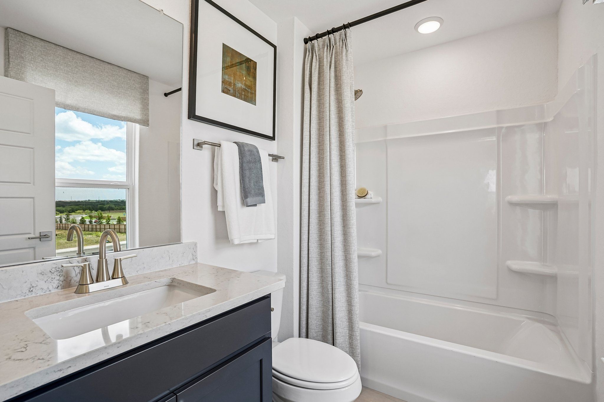 Modern bathroom at Morgan Meadows in San Antonio, TX by Davidson Homes featuring a vanity, quartz countertop, and tub-shower.