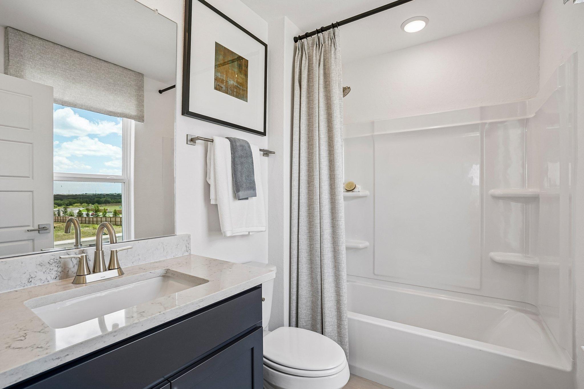 Modern bathroom at Morgan Meadows in San Antonio, TX by Davidson Homes featuring a vanity, quartz countertop, and tub-shower.