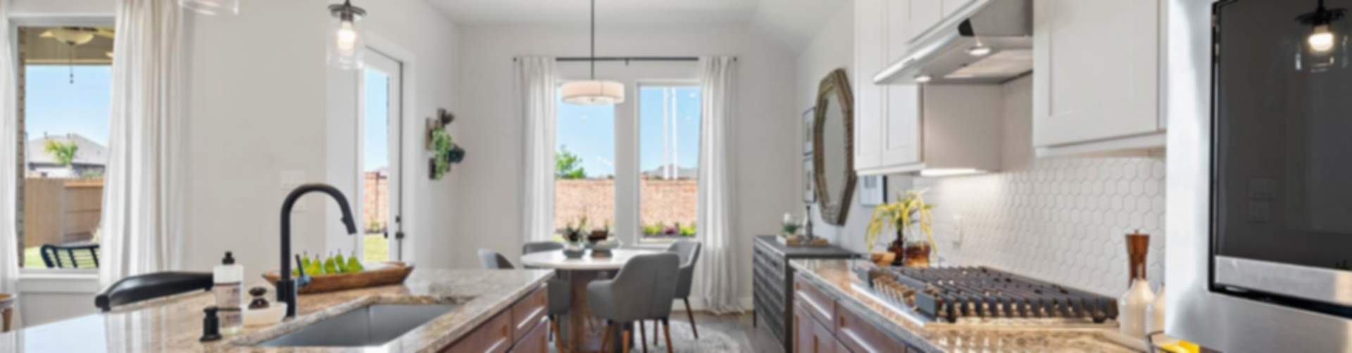 Modern open-concept kitchen and dining in new Beasley home with granite counters, stainless appliances, and pendant lights