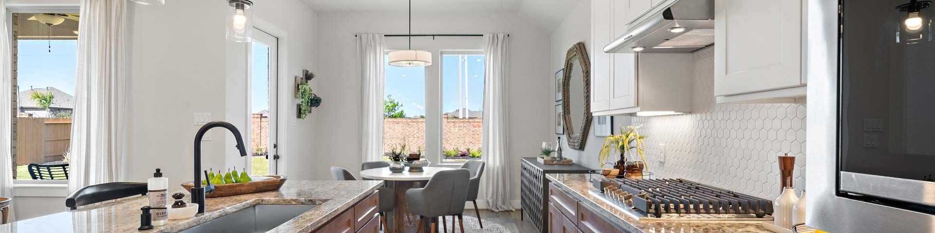 Modern open-concept kitchen and dining in new Beasley home with granite counters, stainless appliances, and pendant lights