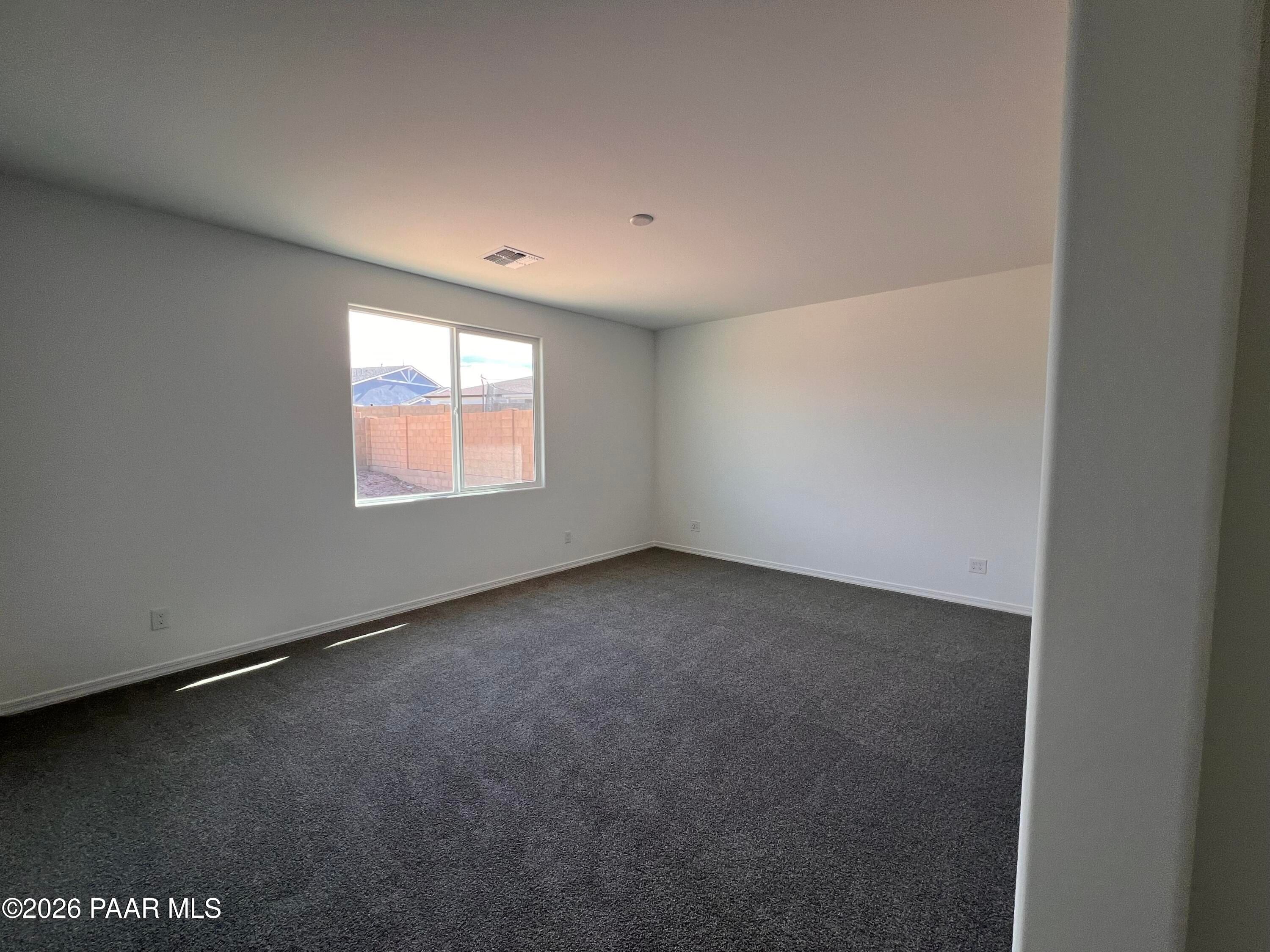 Spacious empty bedroom with large window overlooking fenced backyard, neutral walls, and carpet in Davidson Homes The Summit A, Prescott AZ