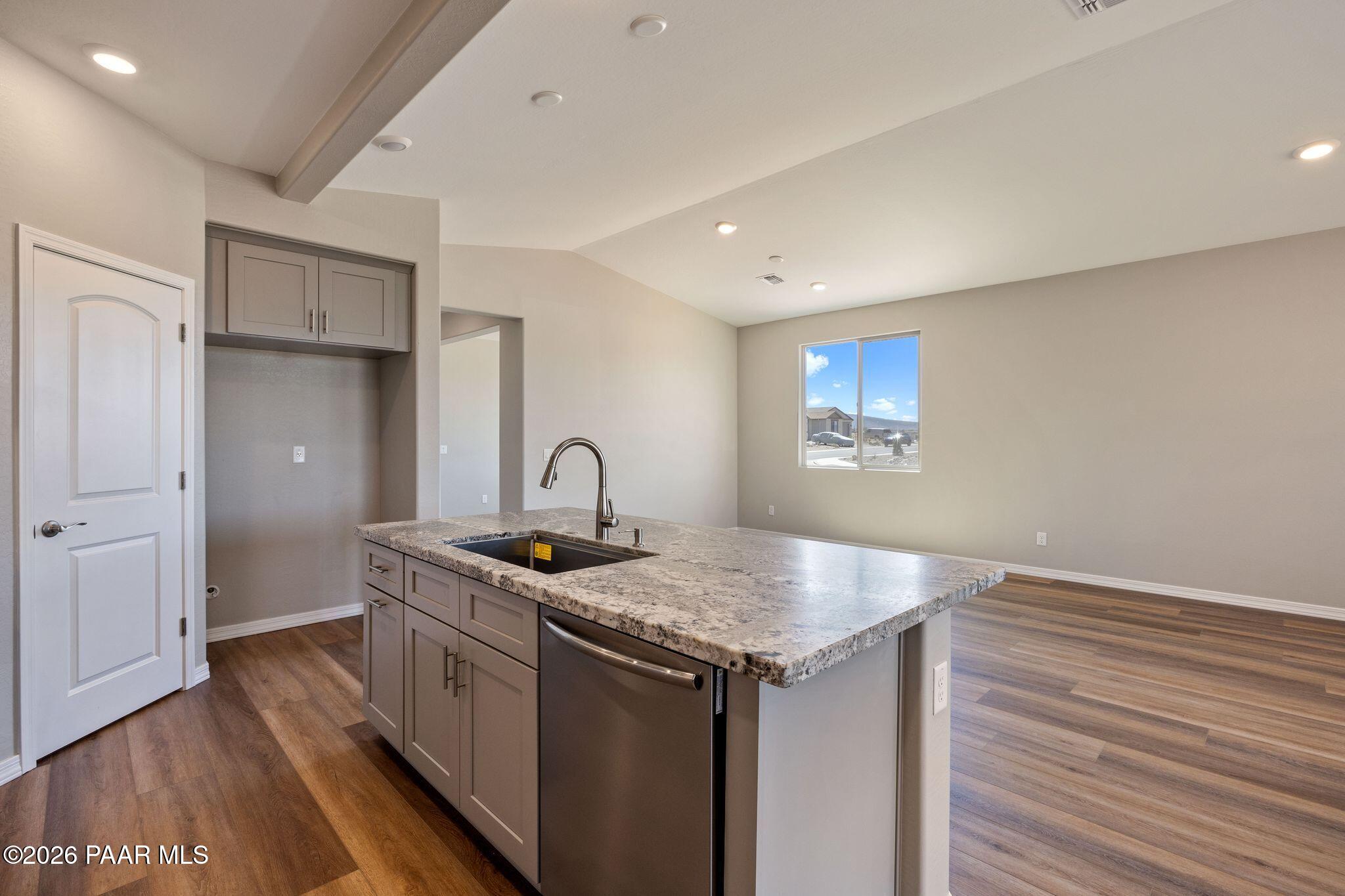 Modern open-concept kitchen with granite island, stainless dishwasher, and large window in The Frontier A, Prescott Valley, AZ