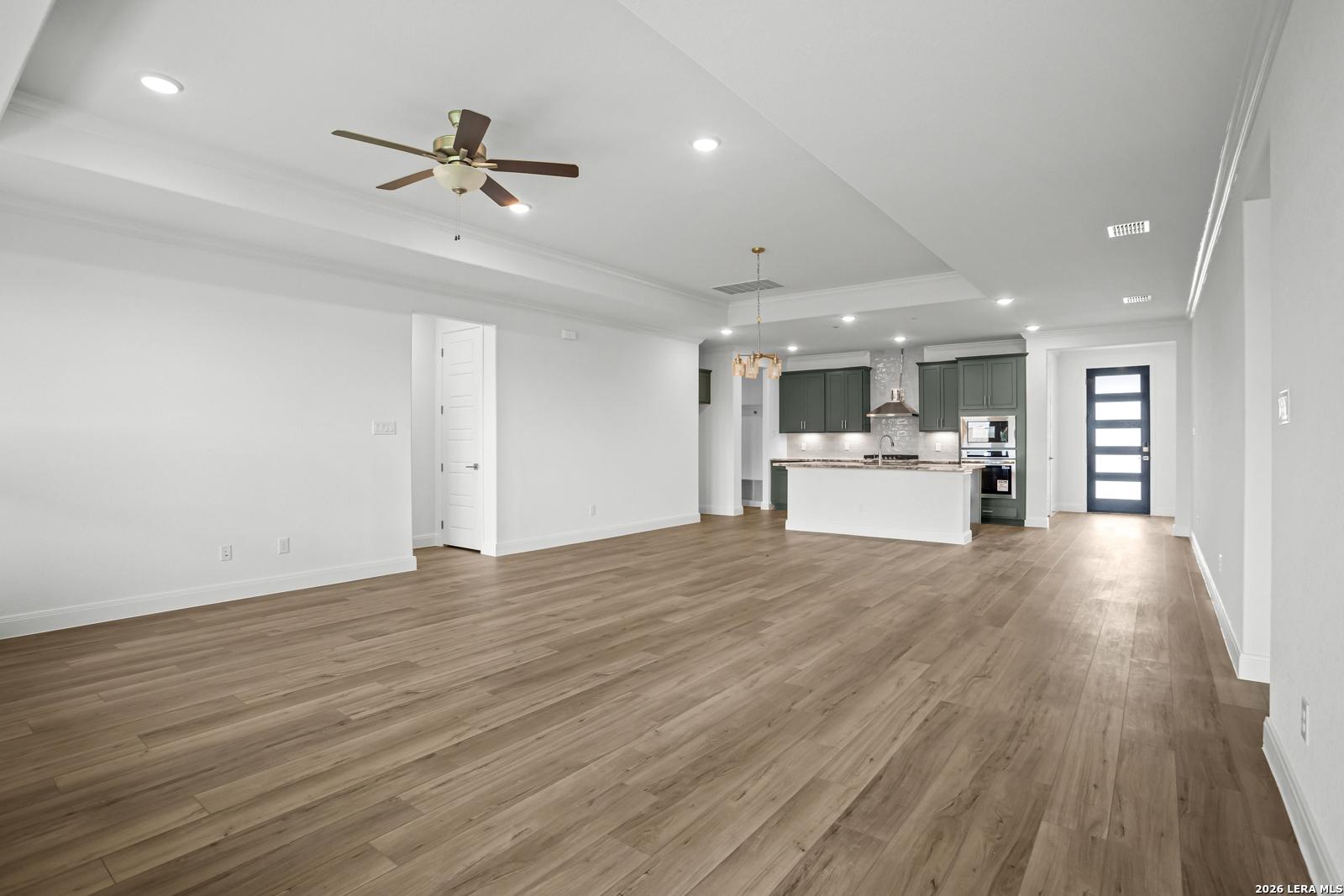 Open-concept living room and kitchen with wood flooring in The Lanier G floor plan at The Reserve at Potranco Oaks.