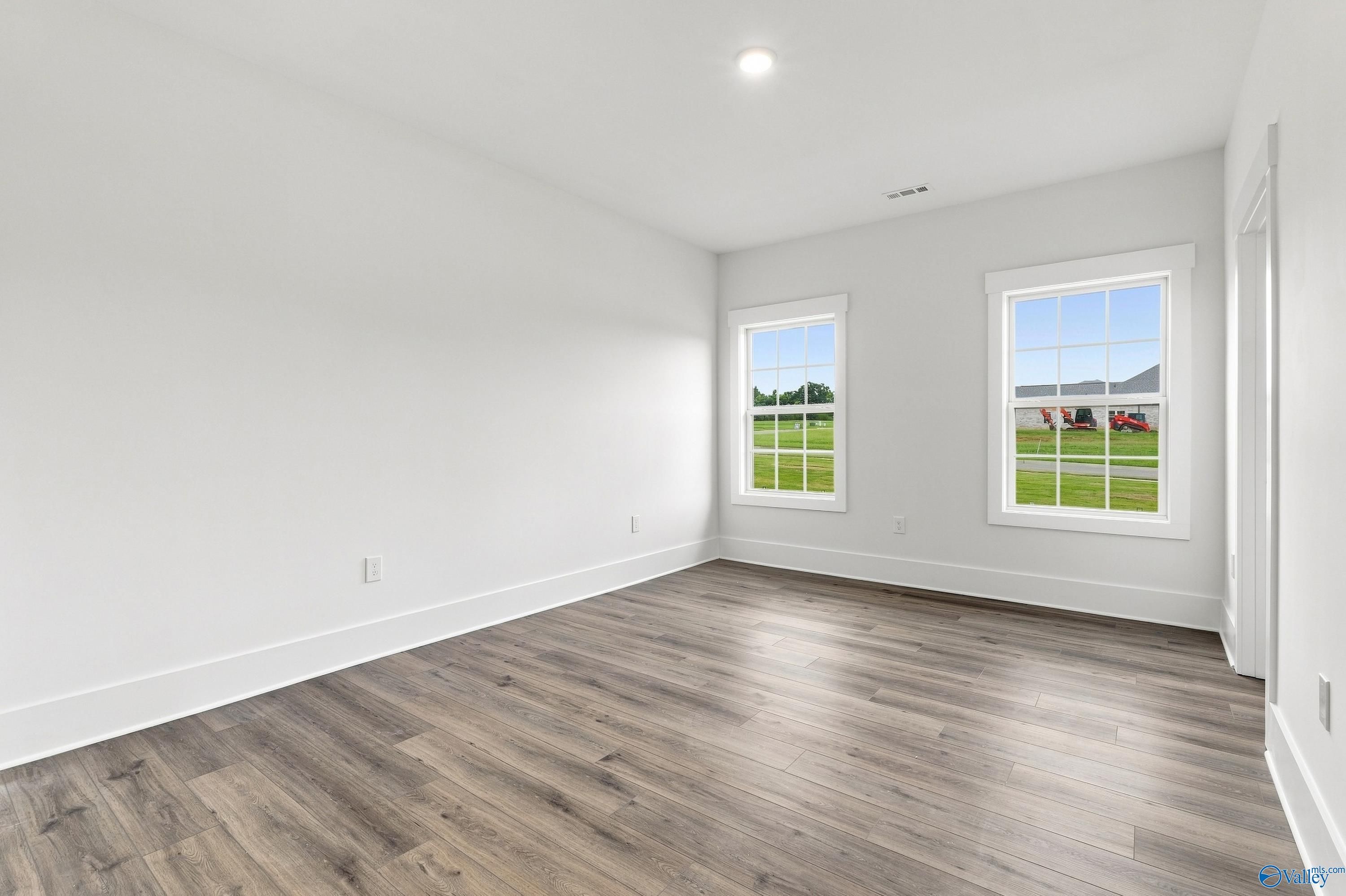 Bright empty bedroom with luxury vinyl plank flooring and white walls in Davidson Homes The Valencia, Huntsville, Alabama