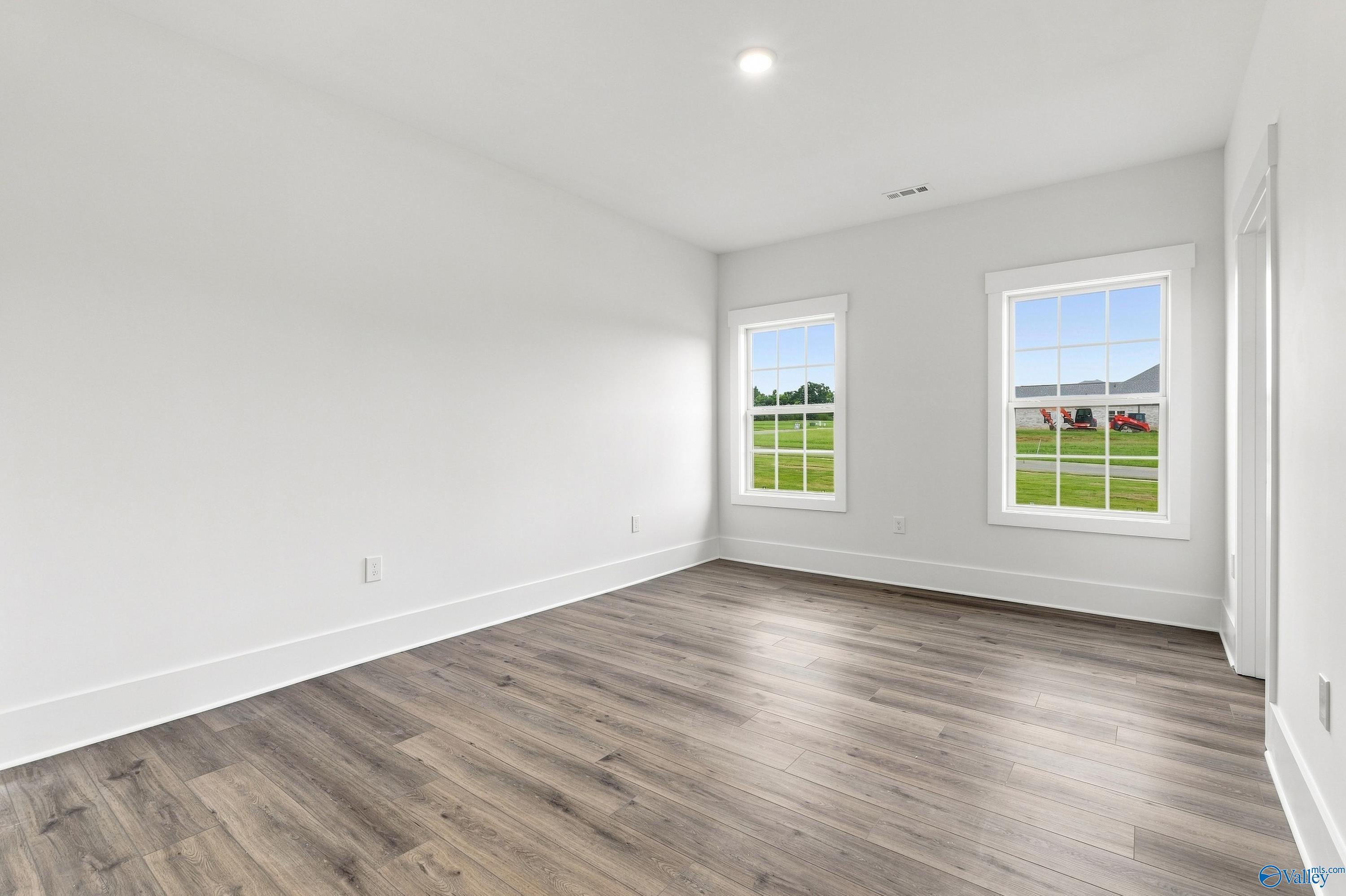 Bright empty bedroom with luxury vinyl plank flooring and white walls in Davidson Homes The Valencia, Huntsville, Alabama