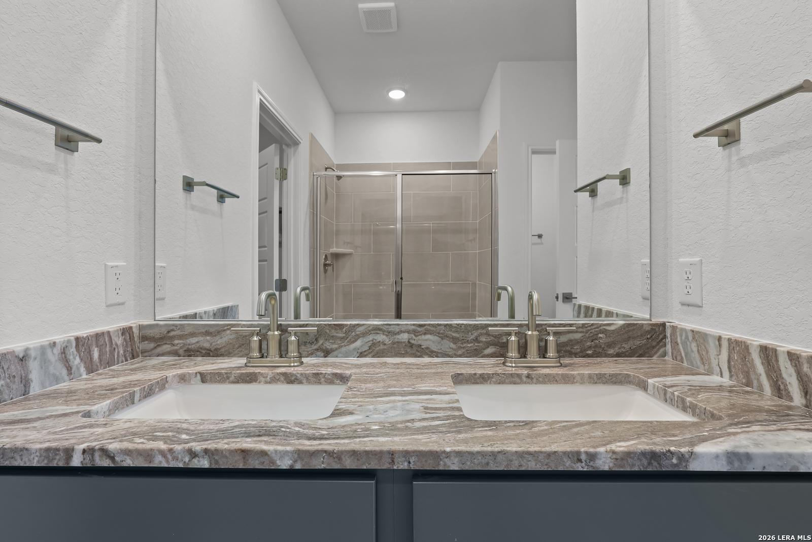 Dual vanity bathroom with marble-style countertops in The Brazos B floor plan by Davidson Homes in Agave, San Antonio.