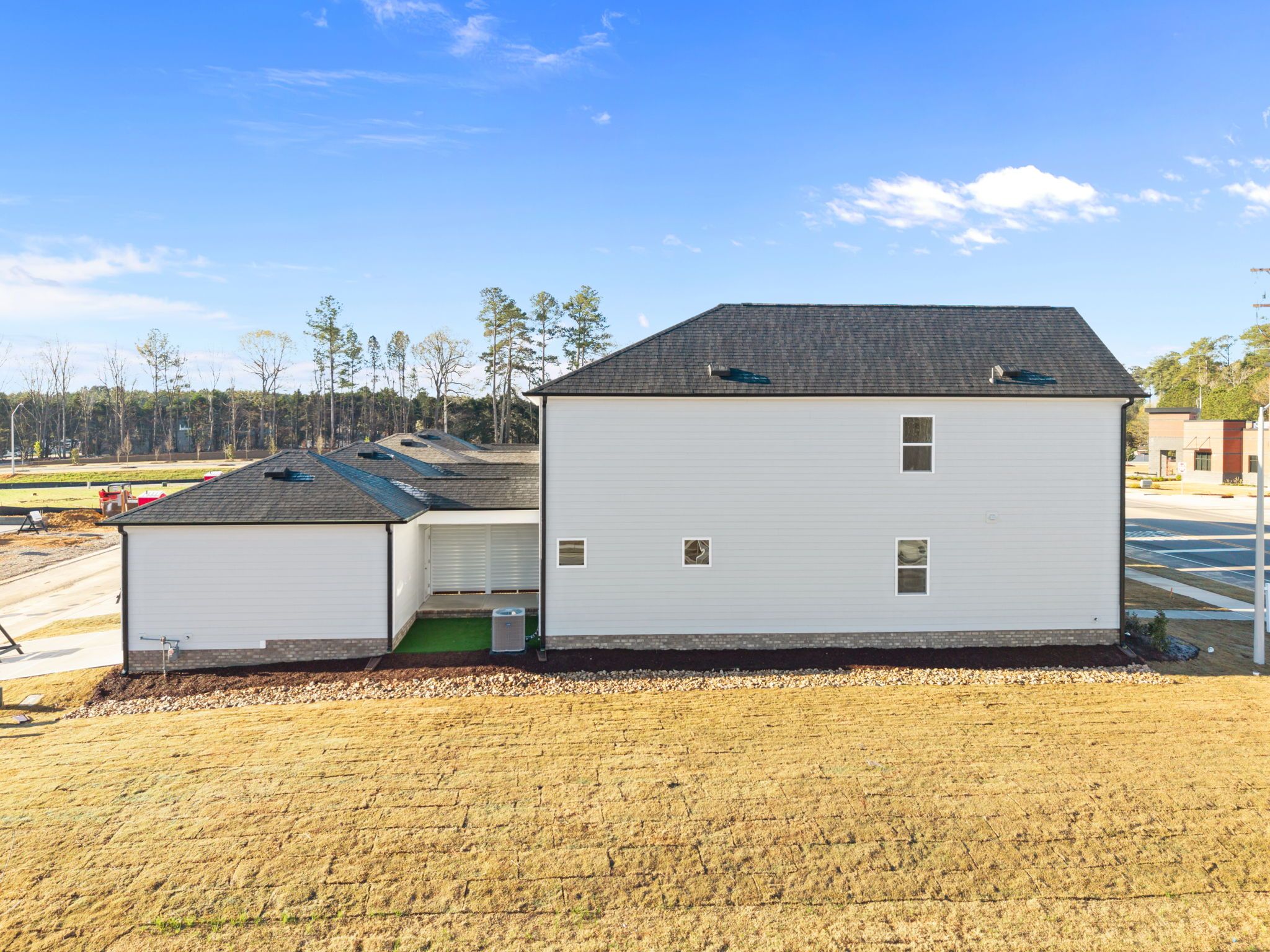 New construction home side exterior at Forestville Yard in Knightdale NC with white siding dark roof and attached garage