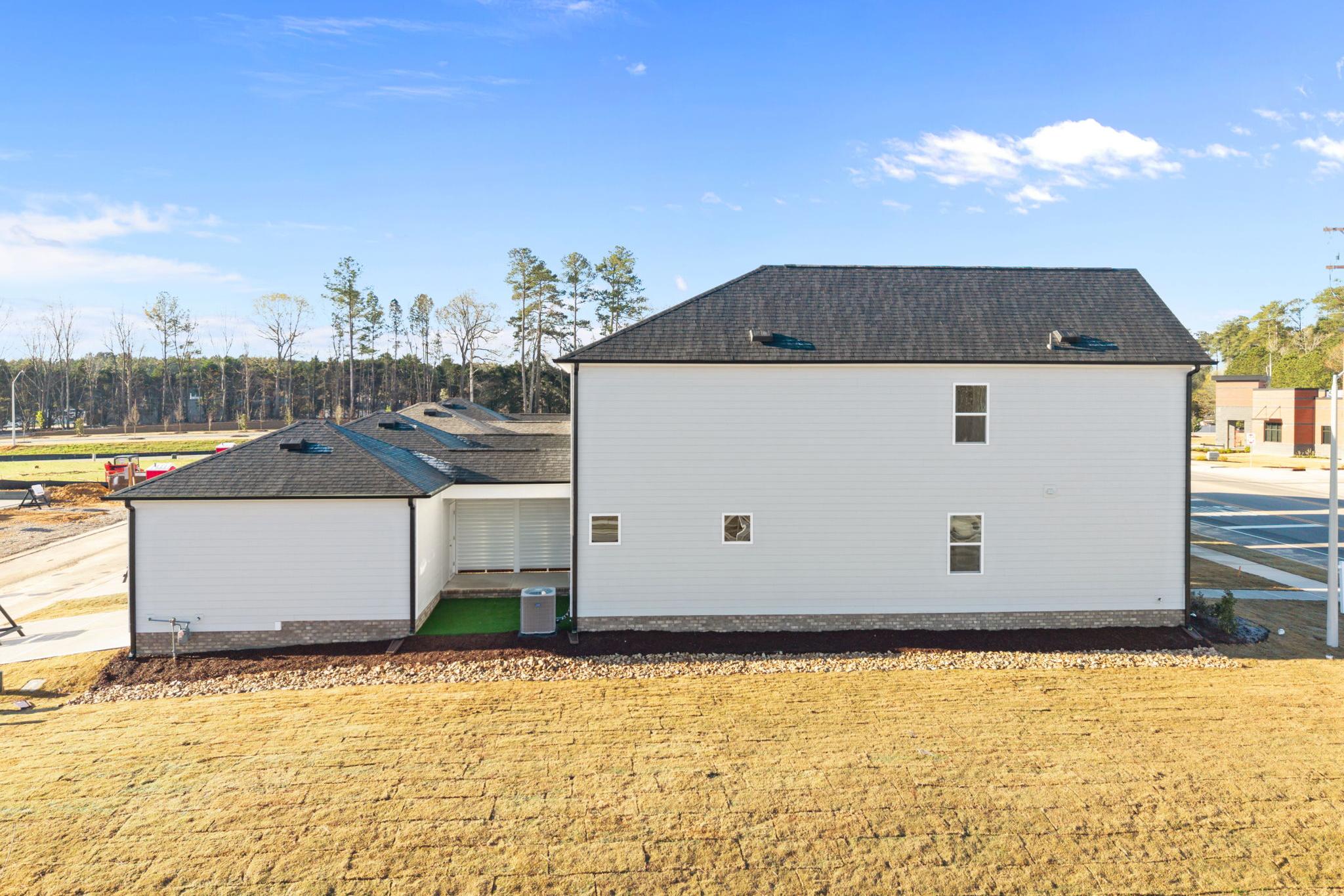New construction home side exterior at Forestville Yard in Knightdale NC with white siding dark roof and attached garage