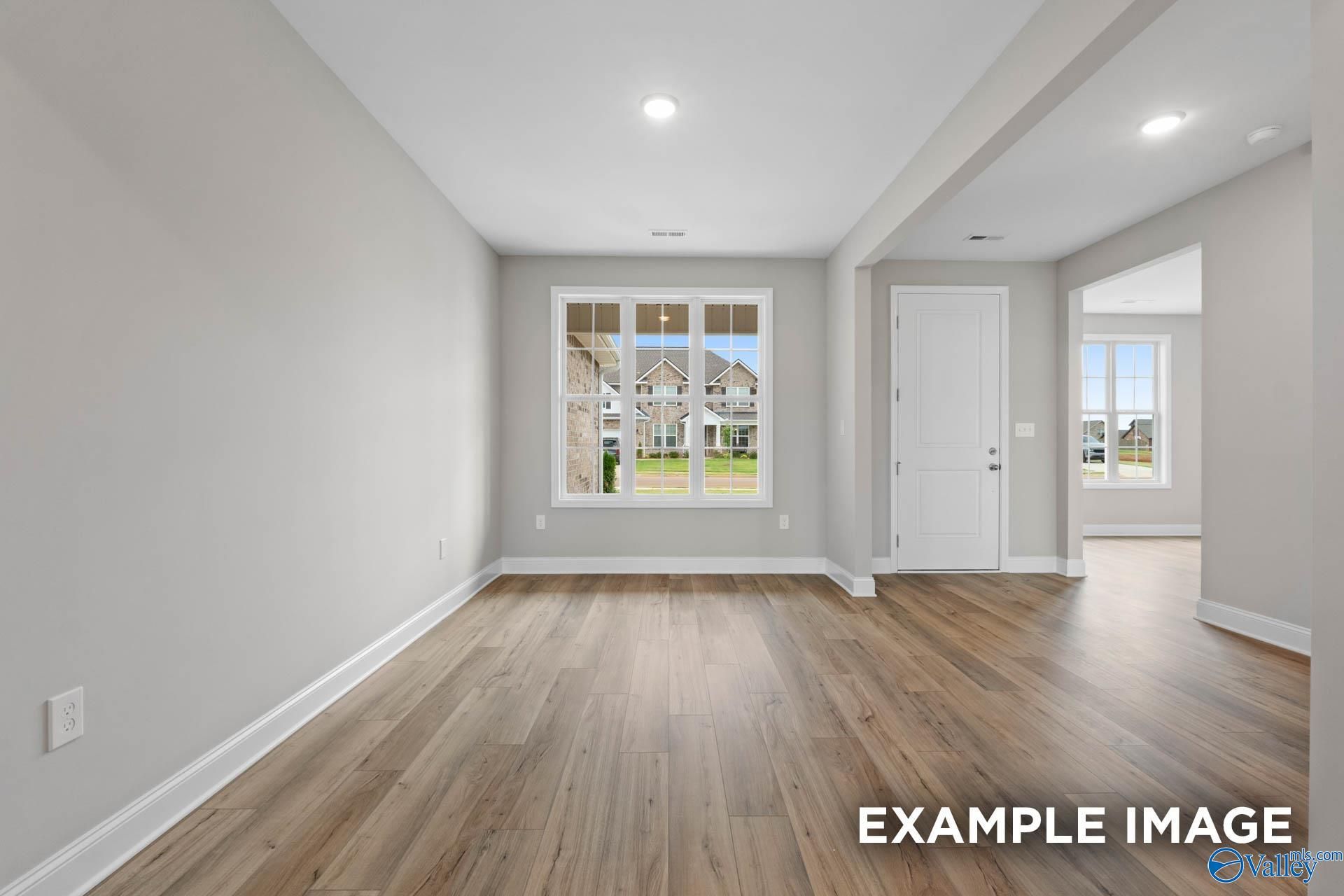 Spacious empty living room with hardwood floors, large windows overlooking backyard in Davidson Homes The Finleigh, Harvest AL