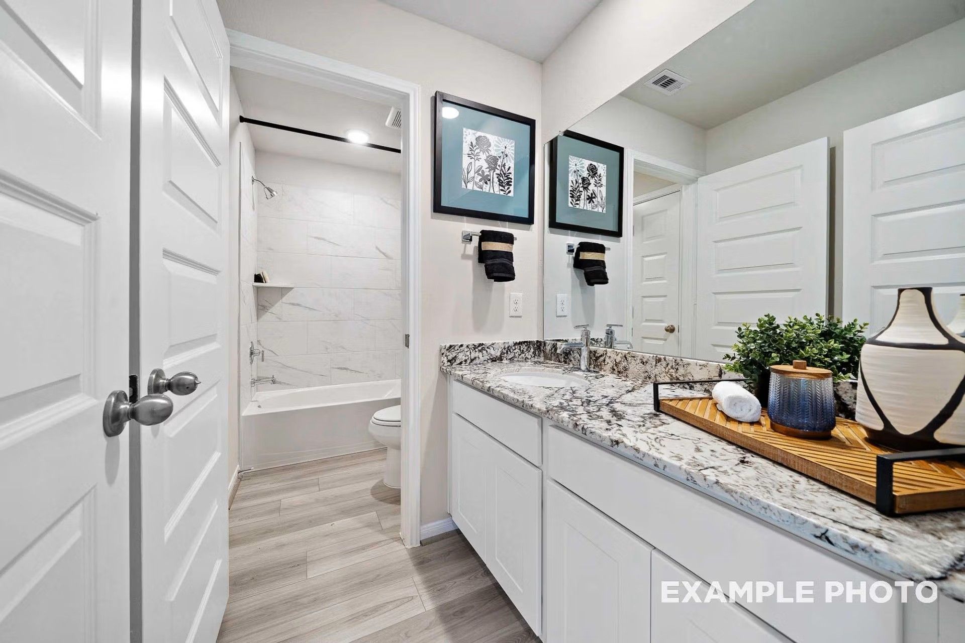 Modern bathroom with granite vanity, white cabinets, and tile shower in Davidson Homes The San Marcos E in Heartland, Texas.