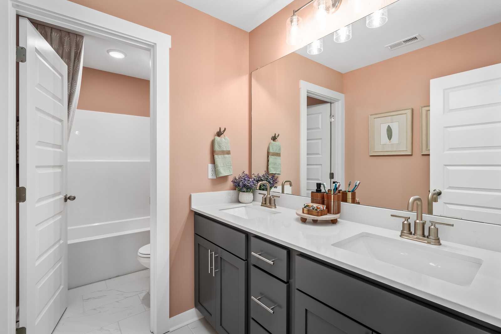 Spacious bathroom at Calista Farms in White House TN with peach walls, white tub, dark gray vanity, and chrome fixtures