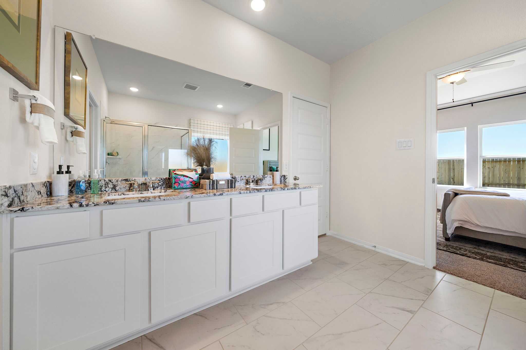 Spacious master bathroom at River Ranch Meadows in Dayton Texas with double vanity granite counters and glass shower