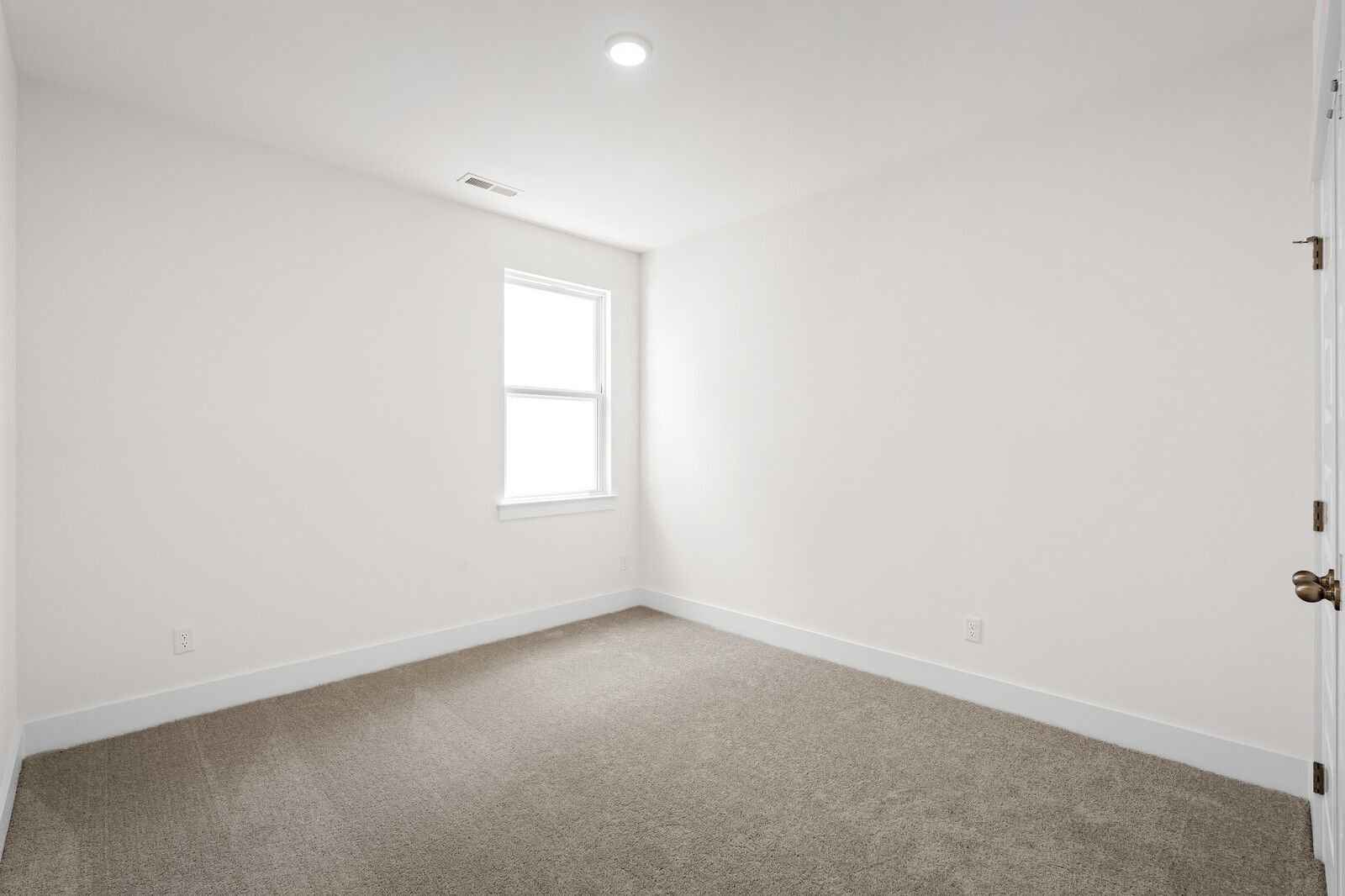 Bright, neutral bedroom in The Cottonwood floor plan by Davidson Homes featuring plush carpeting and natural light.
