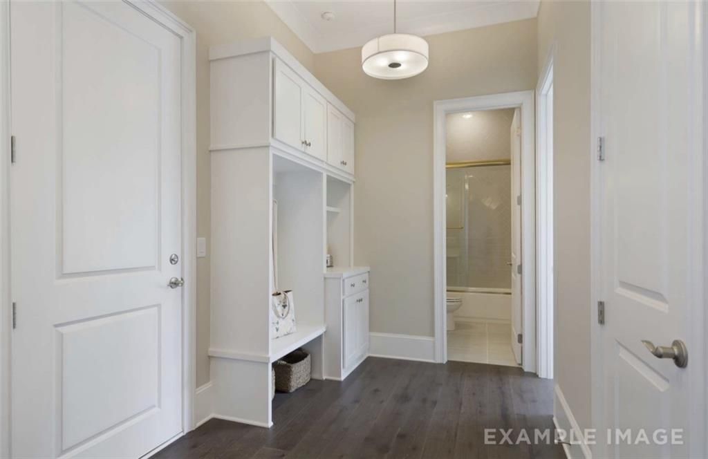 Organized mudroom with white cabinetry, open shelving, and adjacent bathroom in Davidson Homes The Seaside A, Woodstock, Georgia