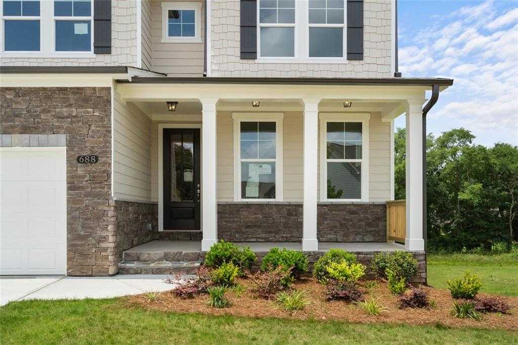 Modern 3-story Davidson Homes exterior with 2-car garage, covered porch, stone accents, and lush landscaping in Wehunt Meadows, Hoschton, Georgia