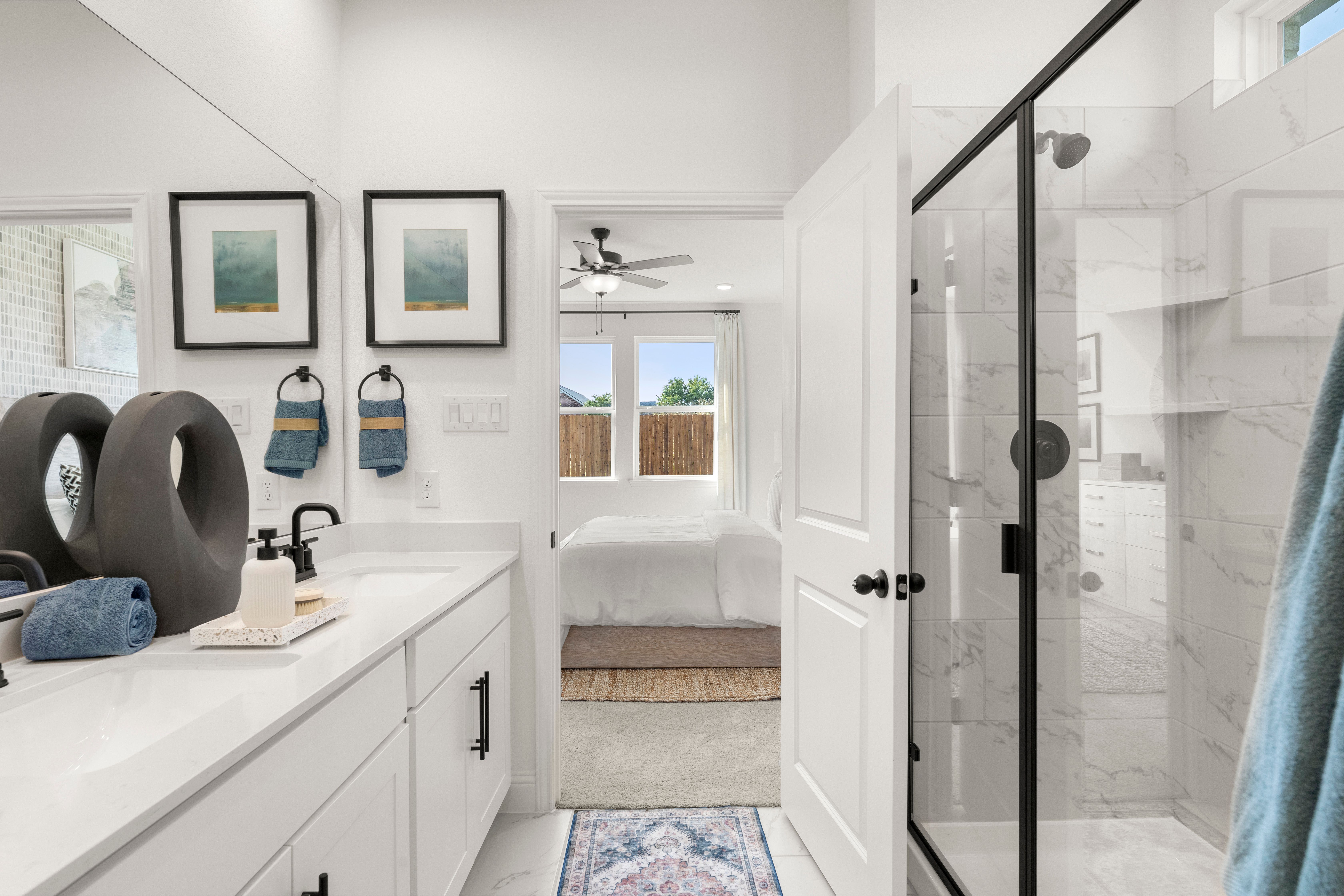 Spacious master bathroom in The Laurel I with double sink vanity, frameless glass shower, and blue accents