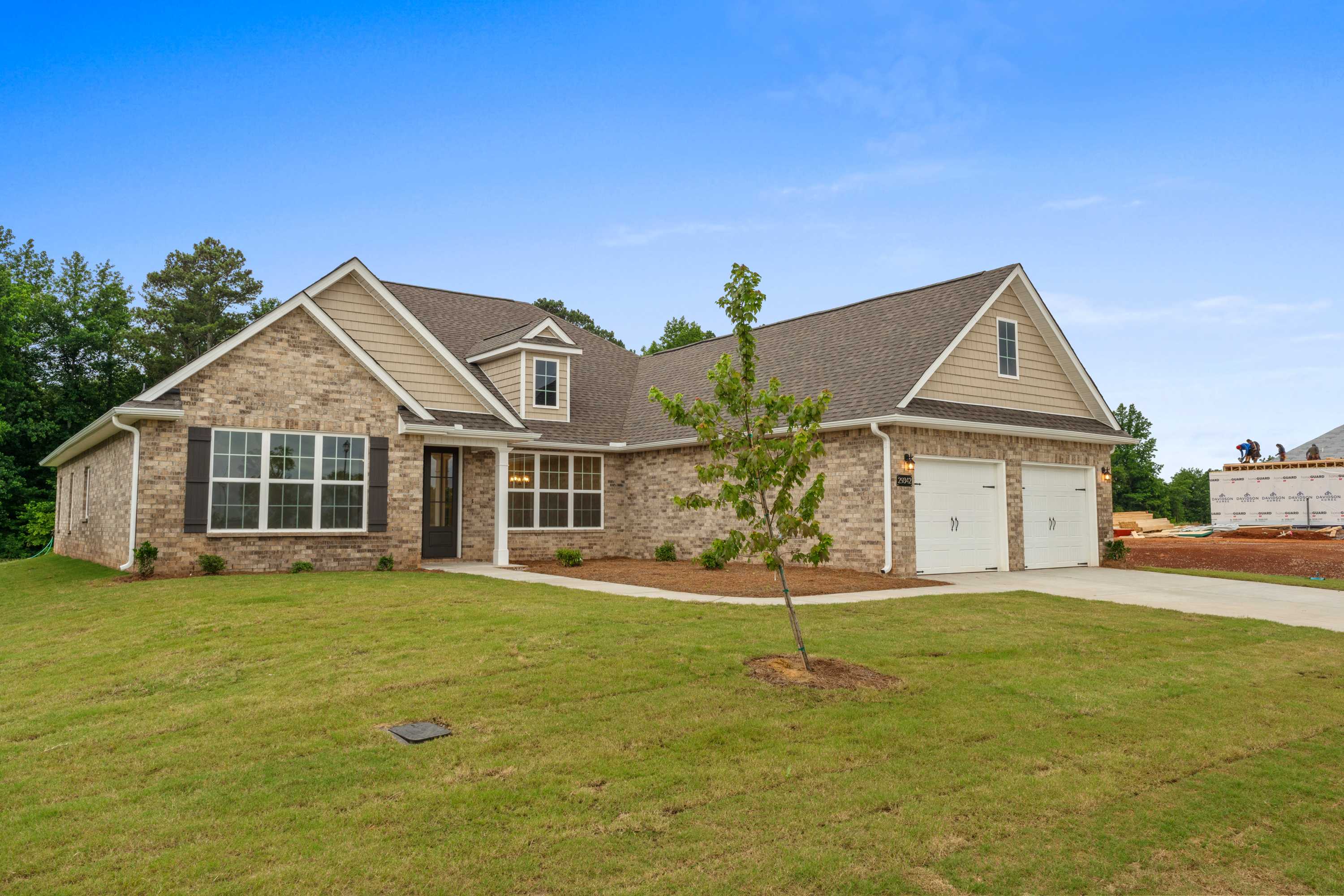 Single-story Oxford home exterior with brick and siding facade, gabled shingle roof, 2-car garage, and lush green lawn in Meridianville AL