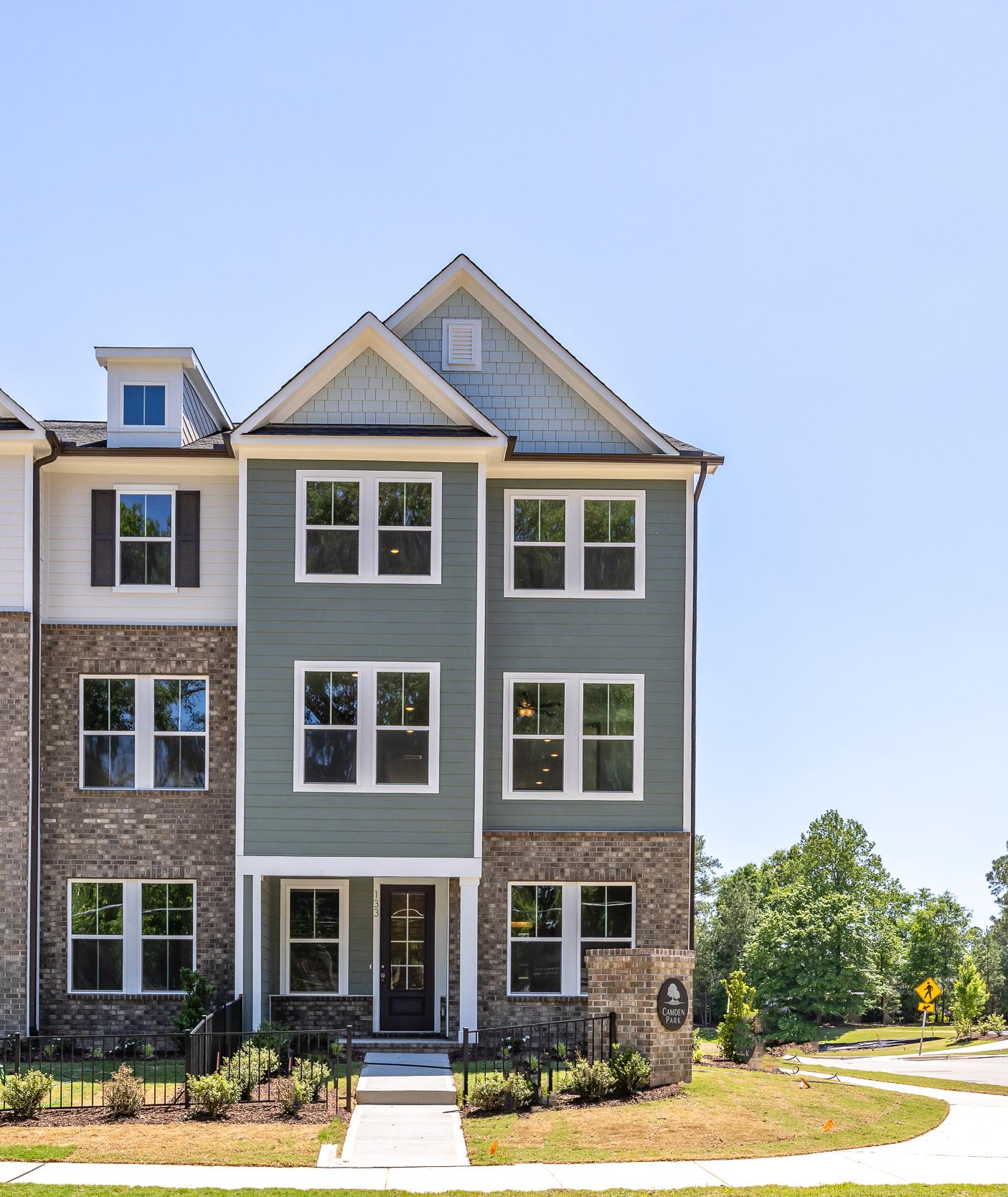 Three-story townhome exterior at Camden Park in Knightdale, NC by Davidson Homes featuring brick and siding facade.