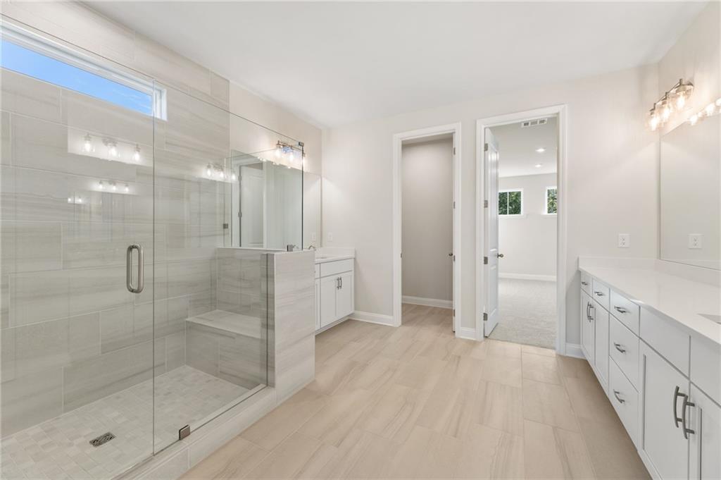 Modern master bathroom with frameless glass shower, double vanity, and tile accents in Davidson Homes The Hampton C, Buford, Georgia