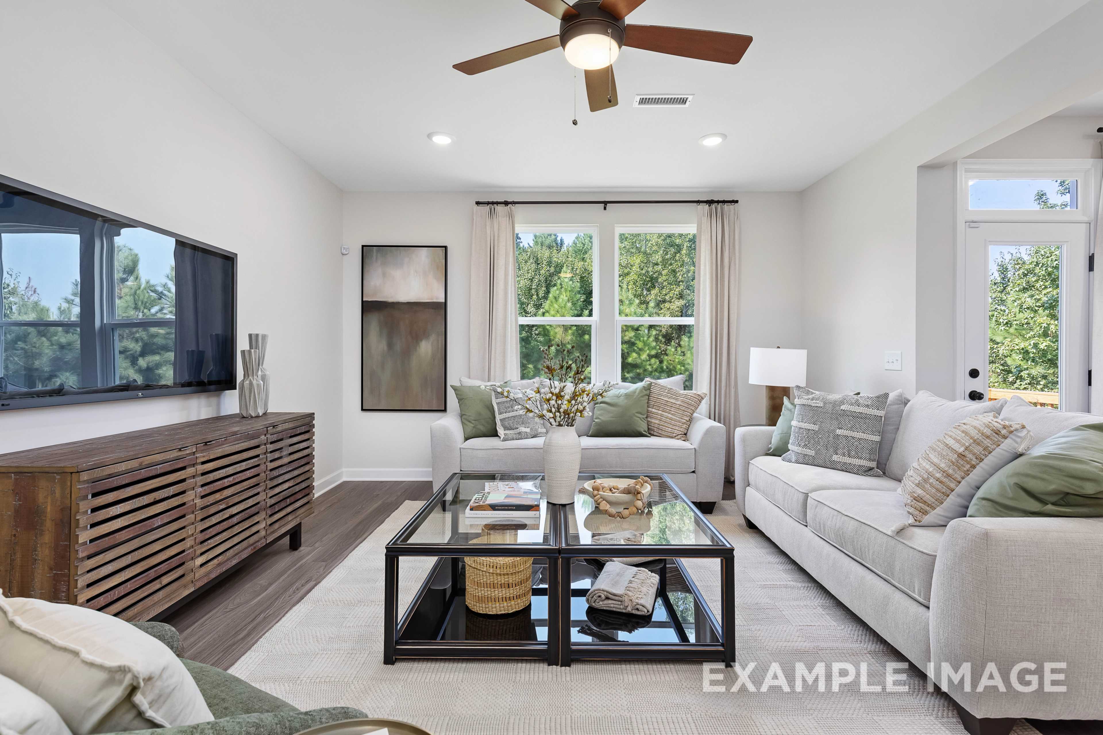 Spacious living room in The Willow B home design by Davidson Homes, featuring beige sectional sofa, glass coffee table, and large windows