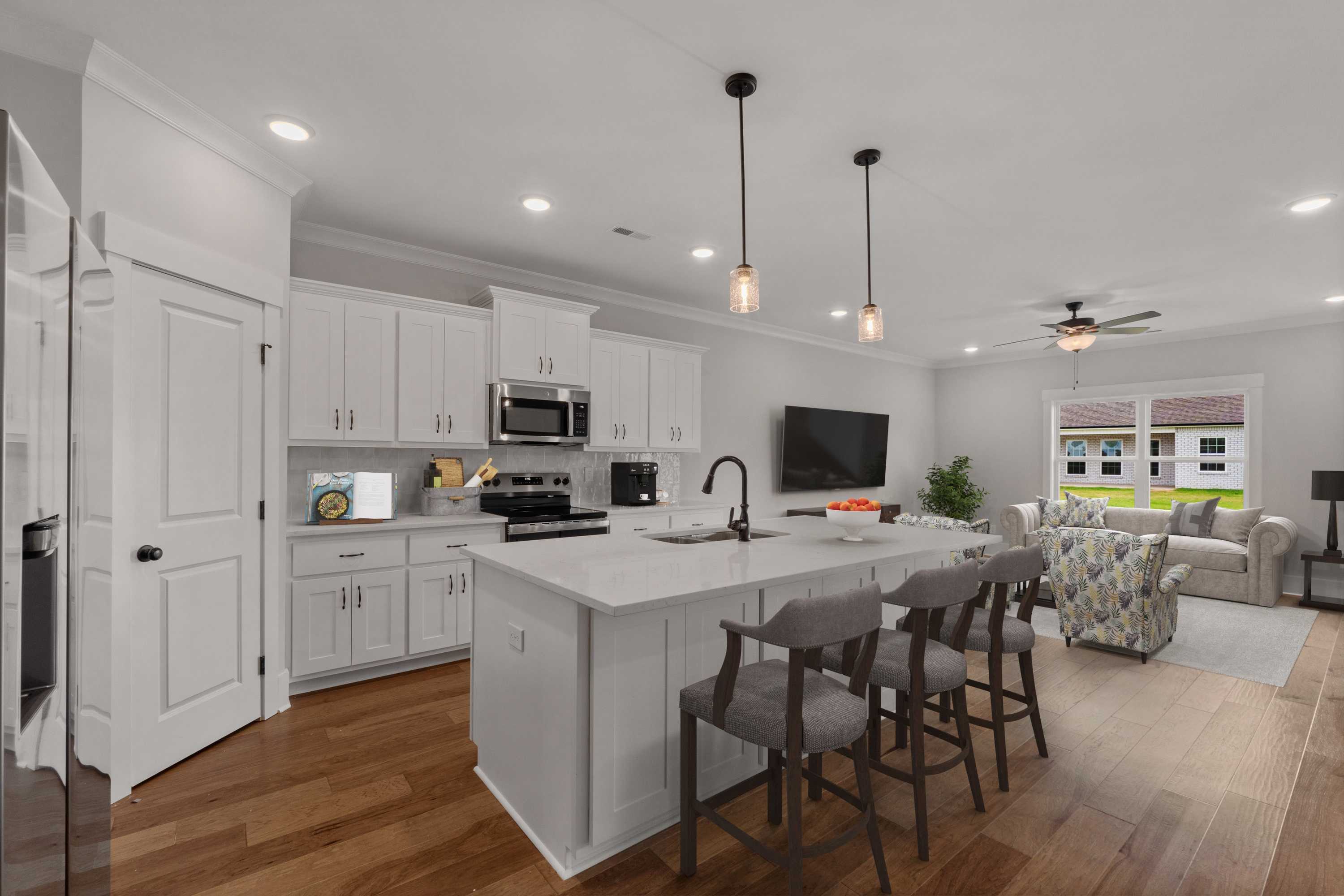Open-concept kitchen and living room at The Villas at Barnett's Crossing in Madison, Alabama with white island, hardwood floors