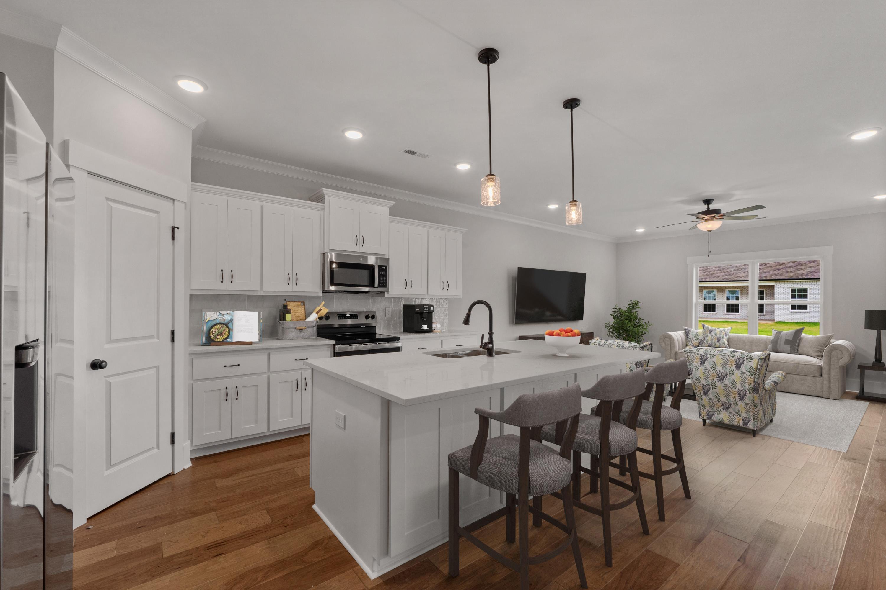 Open-concept kitchen and living room at The Villas at Barnett's Crossing in Madison, Alabama with white island, hardwood floors