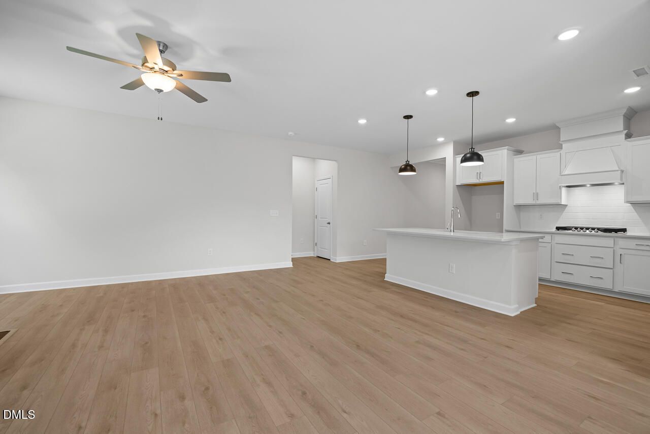 Open-concept living area with white kitchen, island, and pendant lights in Davidson Homes The Daphne D, Zebulon, NC