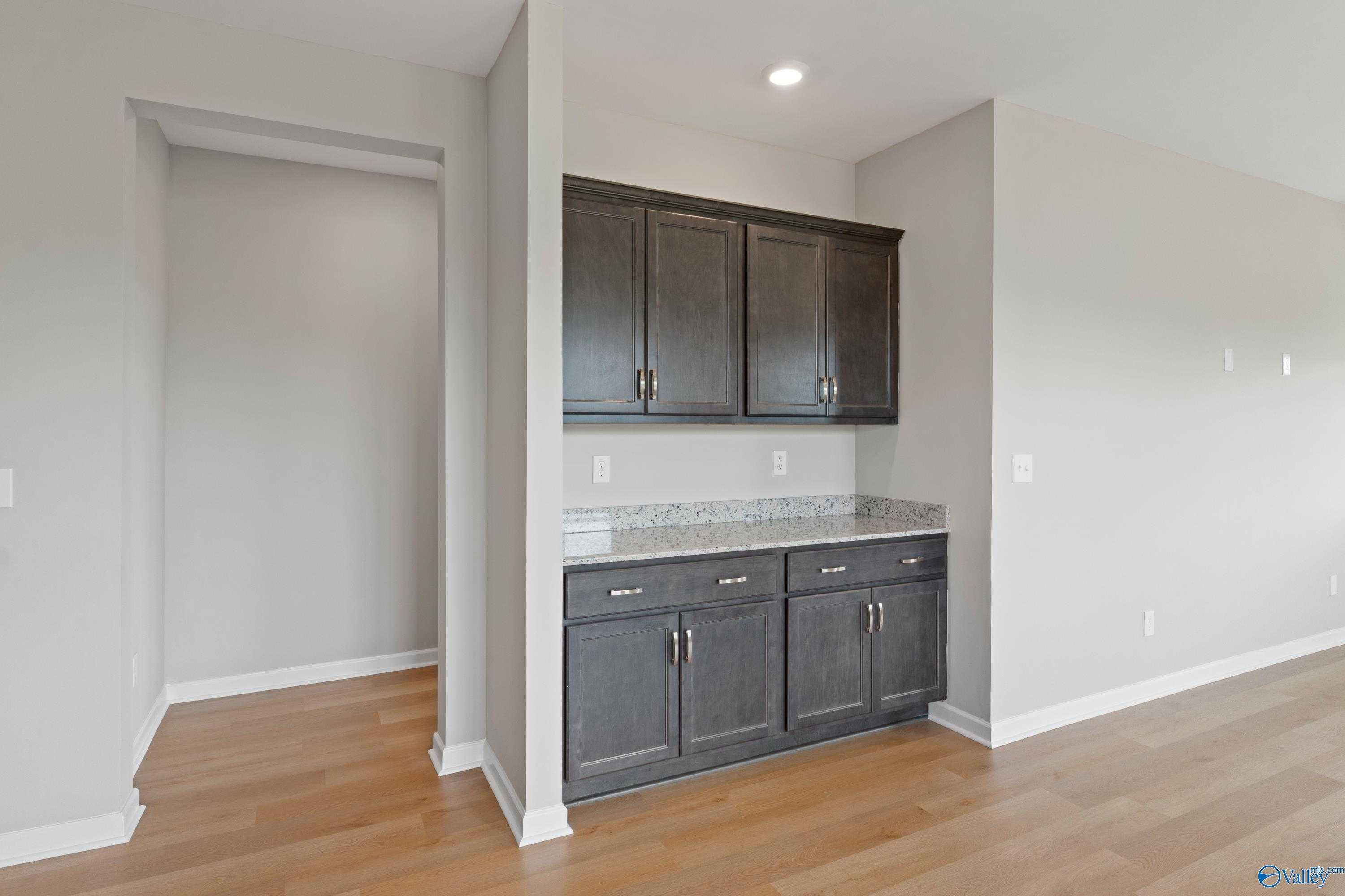 Contemporary kitchen with dark shaker cabinets, quartz counters, and open layout in Evermore Homes The Aurora, Harvest, AL
