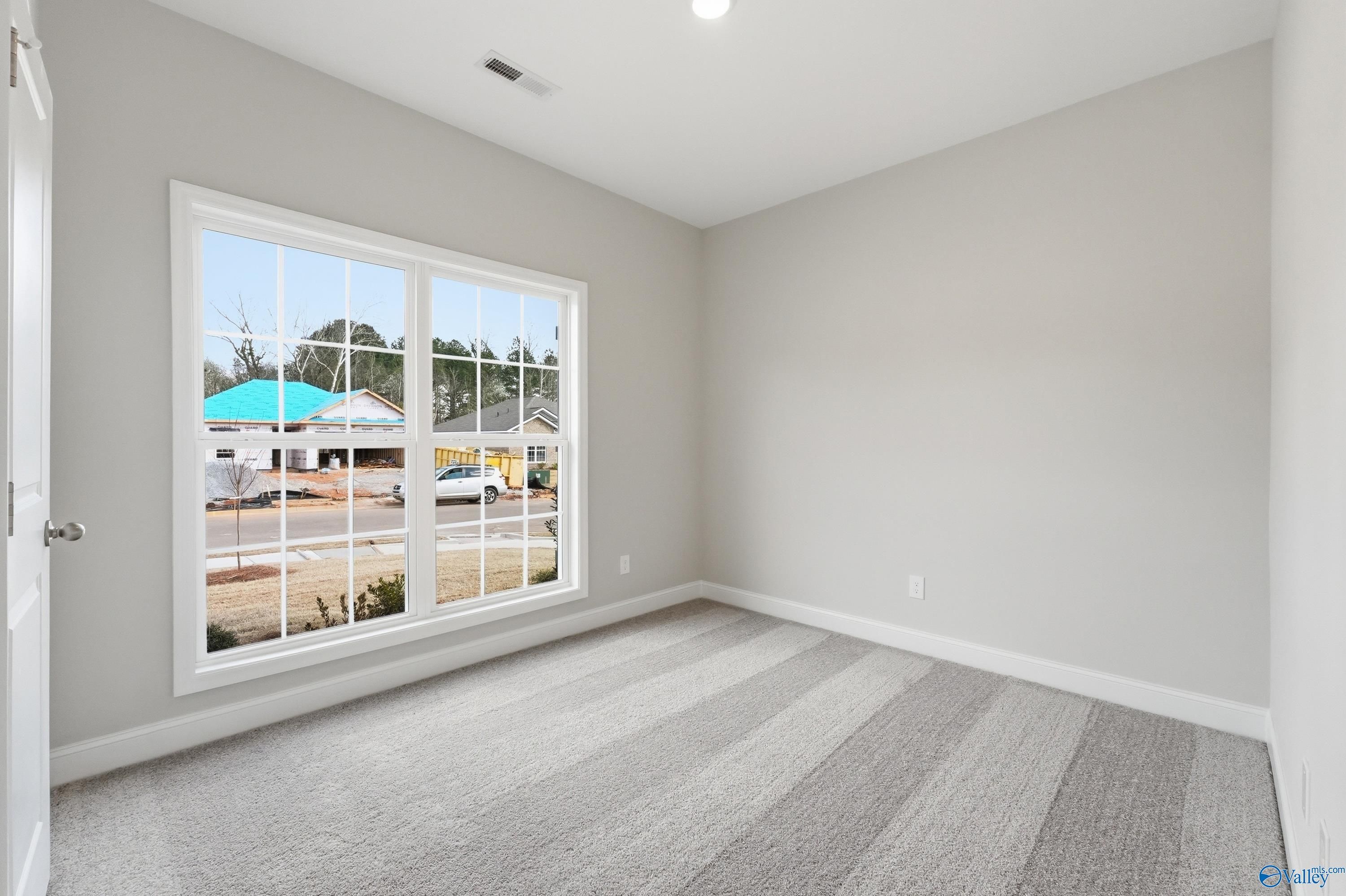 Bright empty bedroom with gray walls, striped carpet, and large window view of Spragins Cove neighborhood in Huntsville, Alabama - The Asheville C