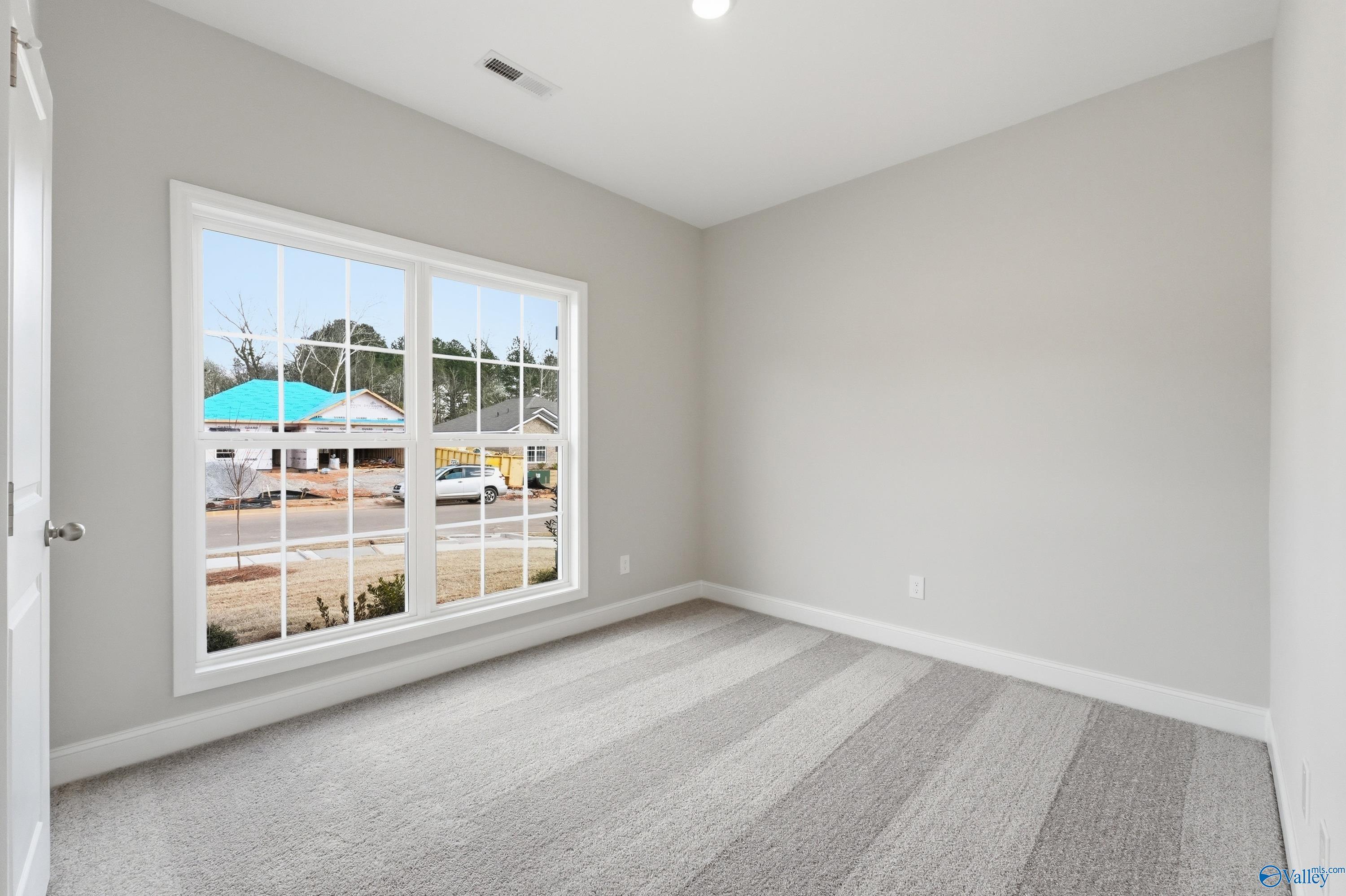 Bright empty bedroom with gray walls, striped carpet, and large window view of Spragins Cove neighborhood in Huntsville, Alabama - The Asheville C