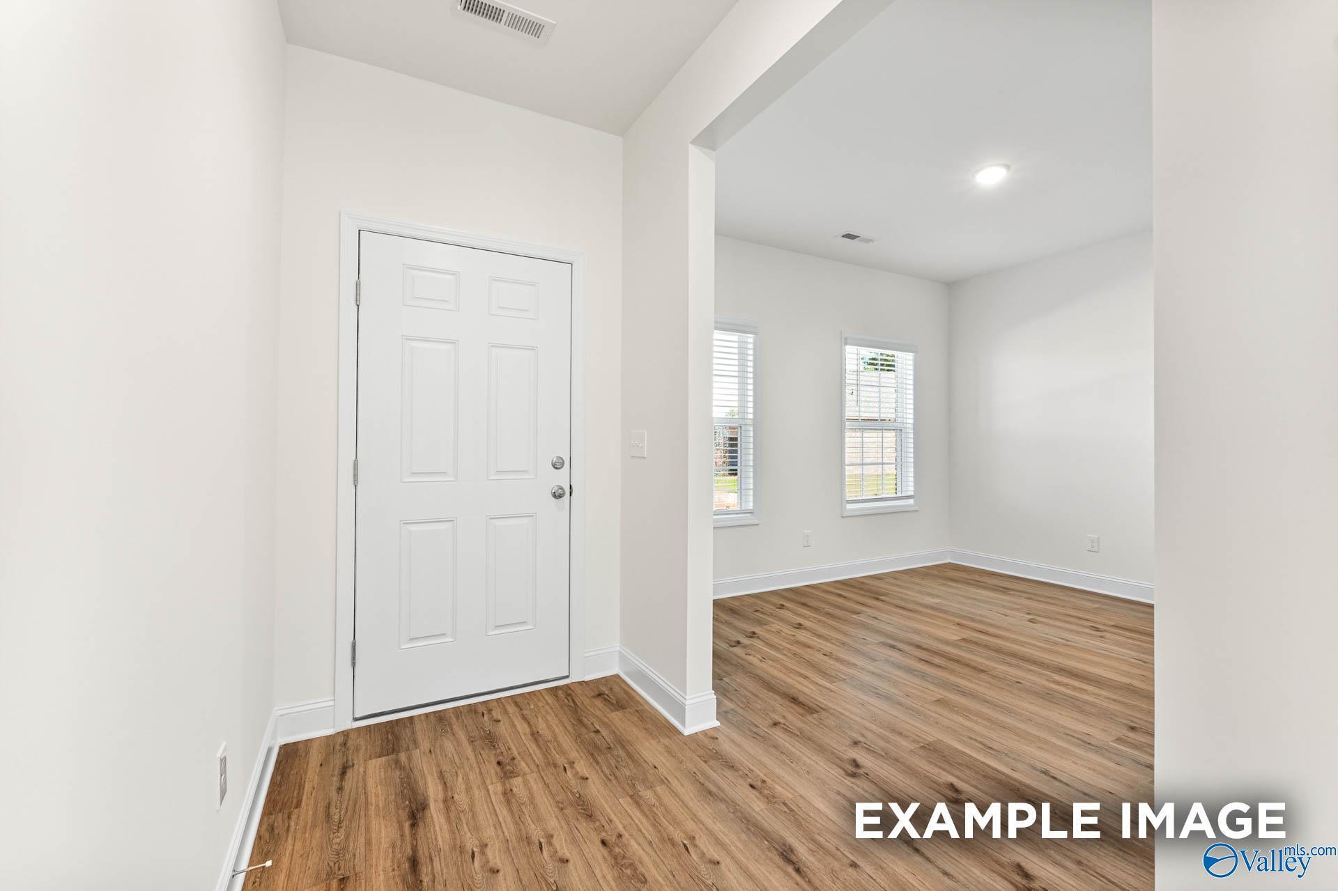 Bright entryway with paneled door, archway, hardwood floors, and large windows in Davidson Homes The Shelby A, Hazel Green, Alabama
