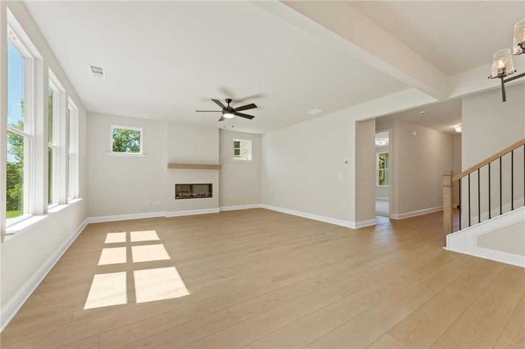 Bright family room with hardwood floors, modern gas fireplace, large windows, and ceiling fan in Davidson Homes The Hickory E, Buford GA