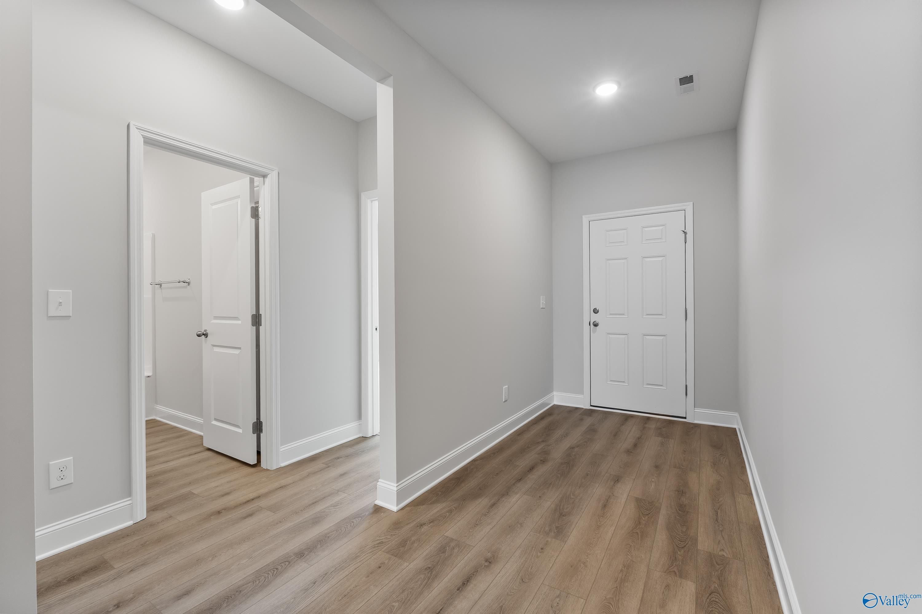 Bright hallway with luxury vinyl plank flooring, bathroom access, and white doors in 4-bedroom Davidson Homes The Daphne, Hazel Green, AL