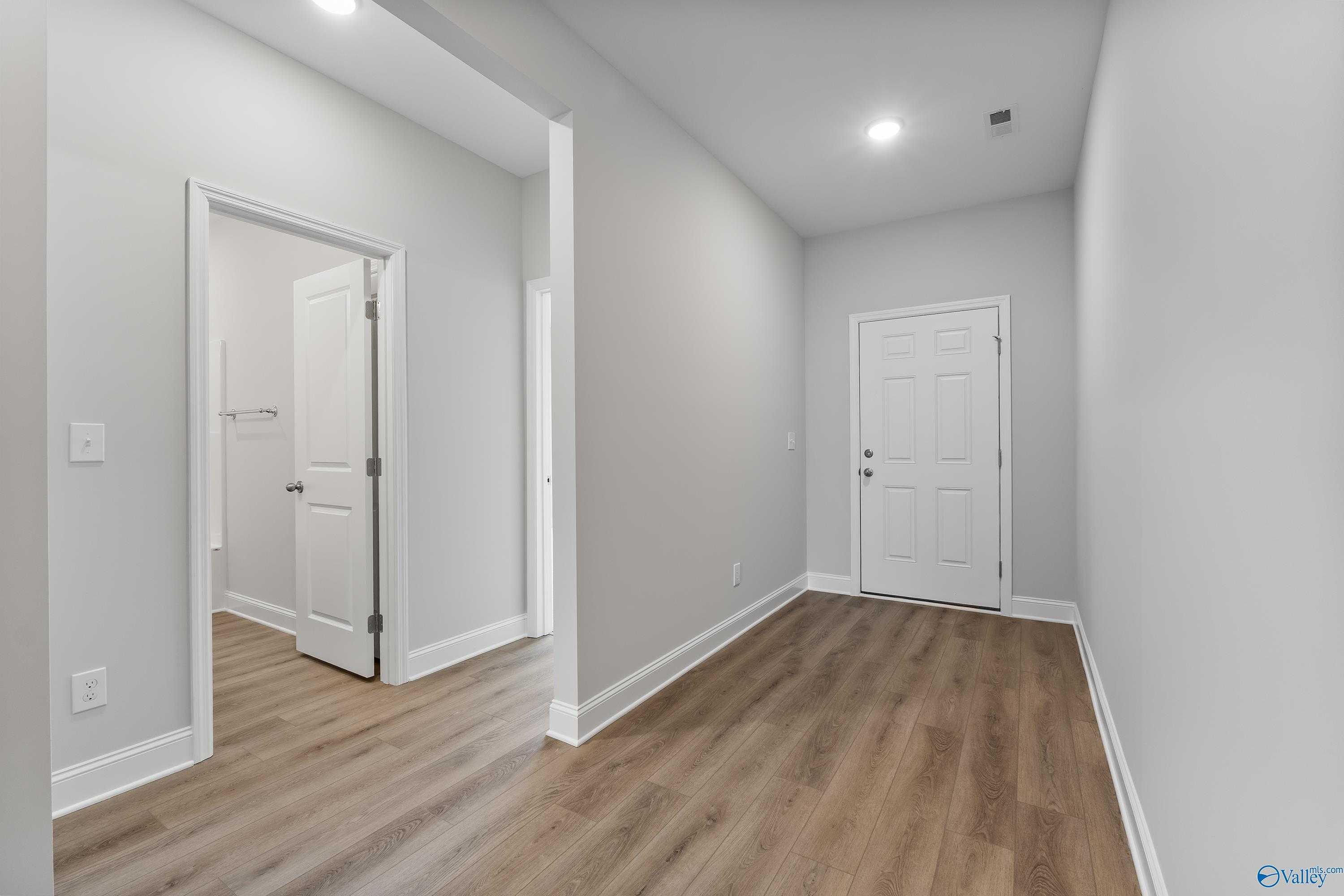 Bright hallway with luxury vinyl plank flooring, bathroom access, and white doors in 4-bedroom Davidson Homes The Daphne, Hazel Green, AL