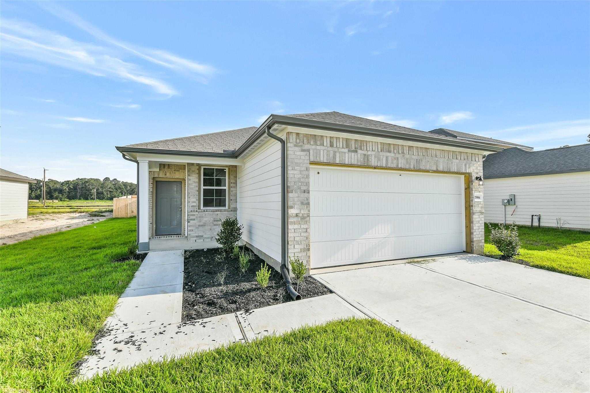 Modern single-story 4-bedroom home with 2-car garage, gray siding, and landscaped yard in Liberty Estates, Cleveland, Texas