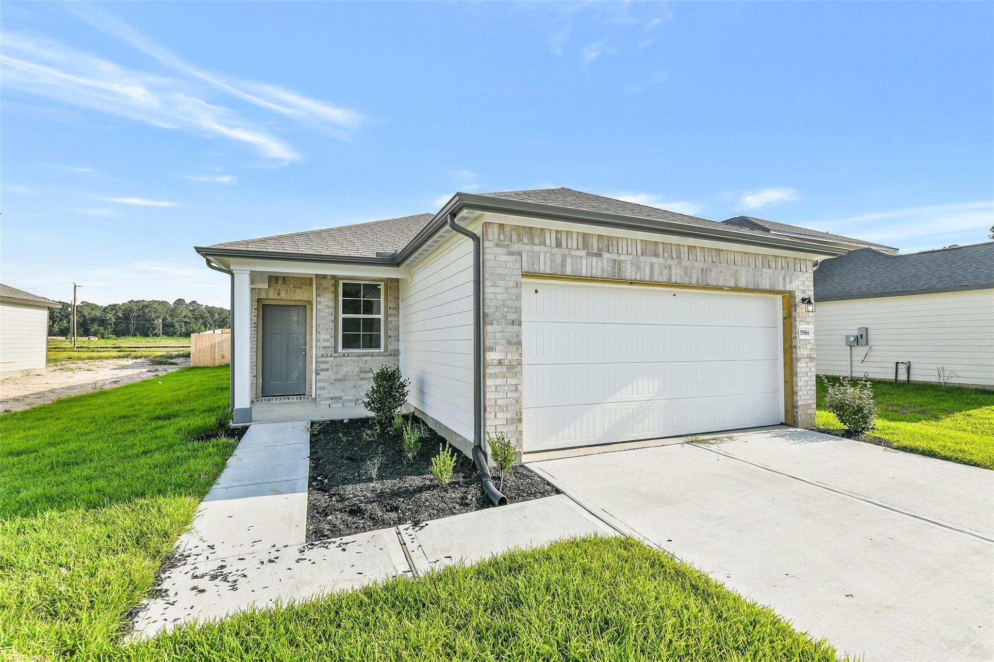 Modern single-story 4-bedroom home with 2-car garage, gray siding, and landscaped yard in Liberty Estates, Cleveland, Texas